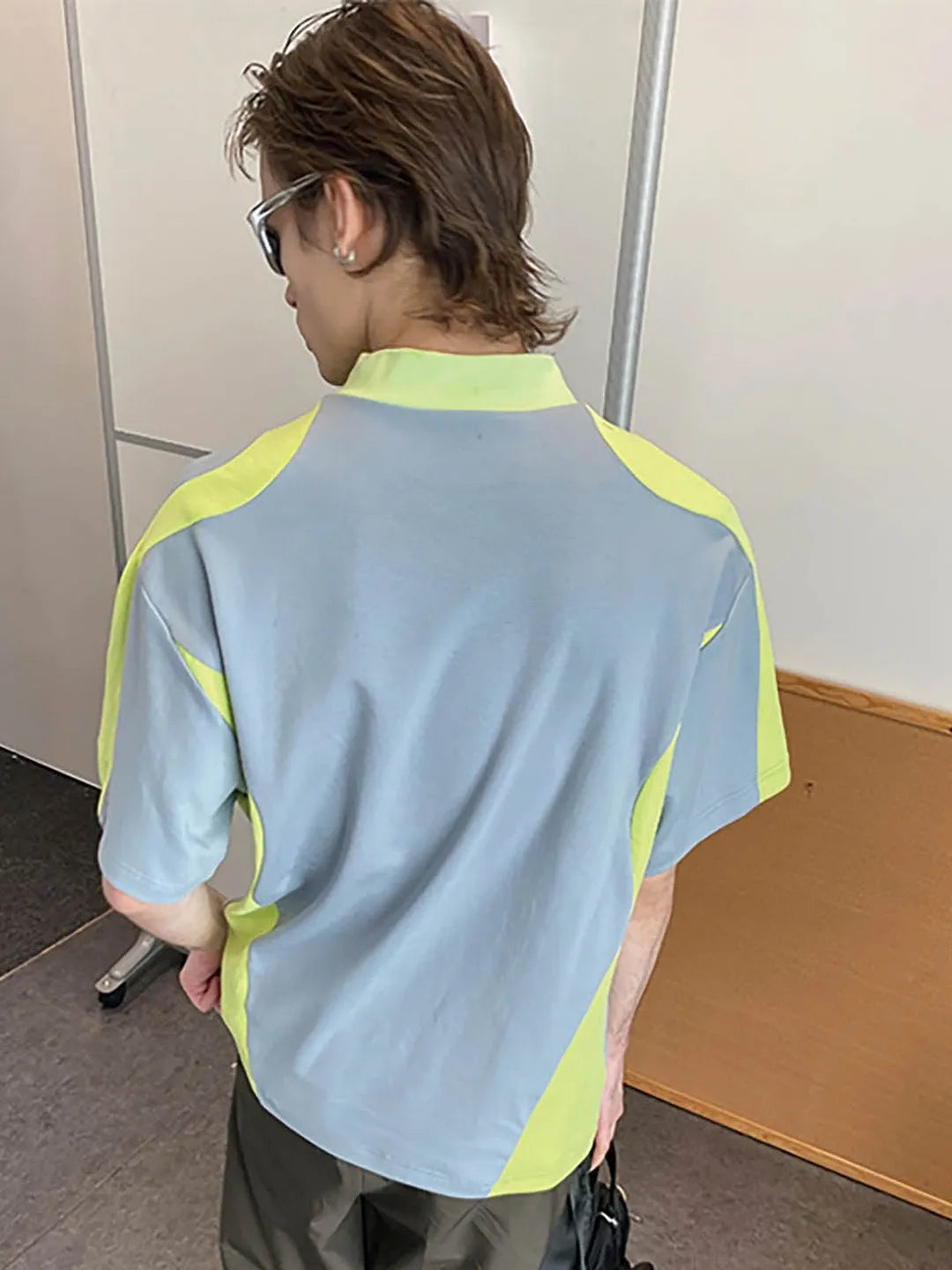 Person wearing a light blue and green shirt in an indoor setting