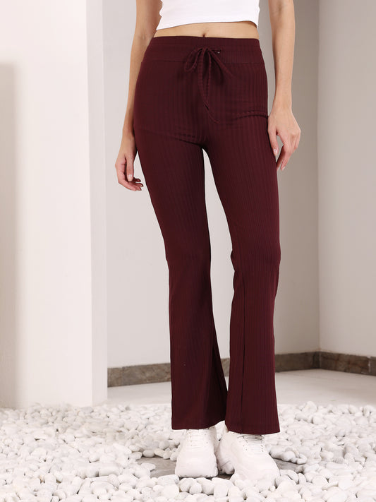 A person standing in a maroon flare pants with a drawstring waist, paired with white sneakers.