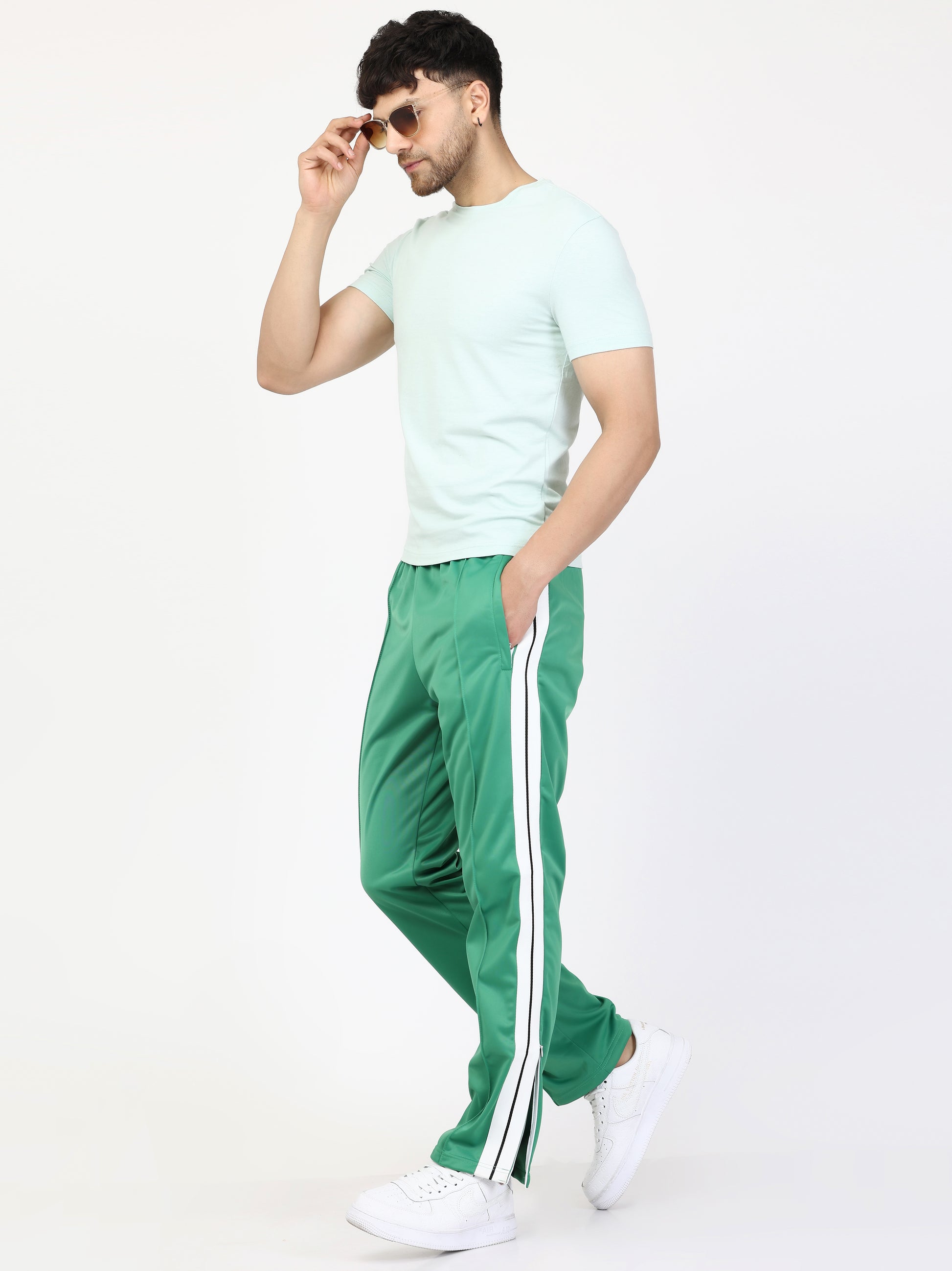 Green track pants with white side stripes and an elasticated waistband, with pockets.