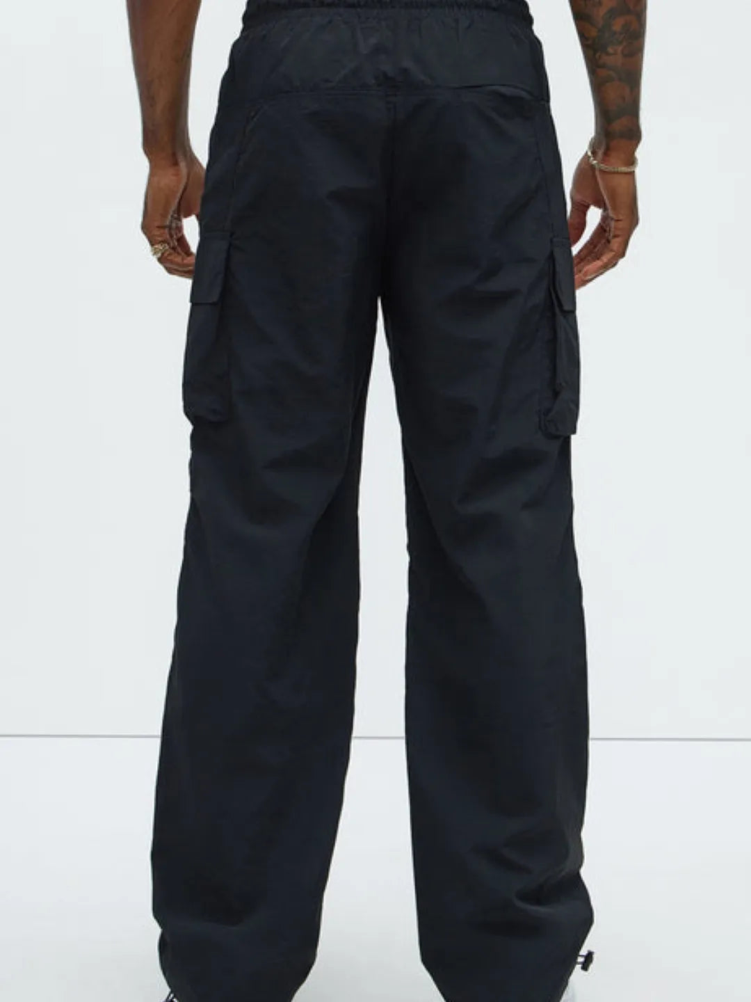 Person wearing black cargo pants with pockets on a white background