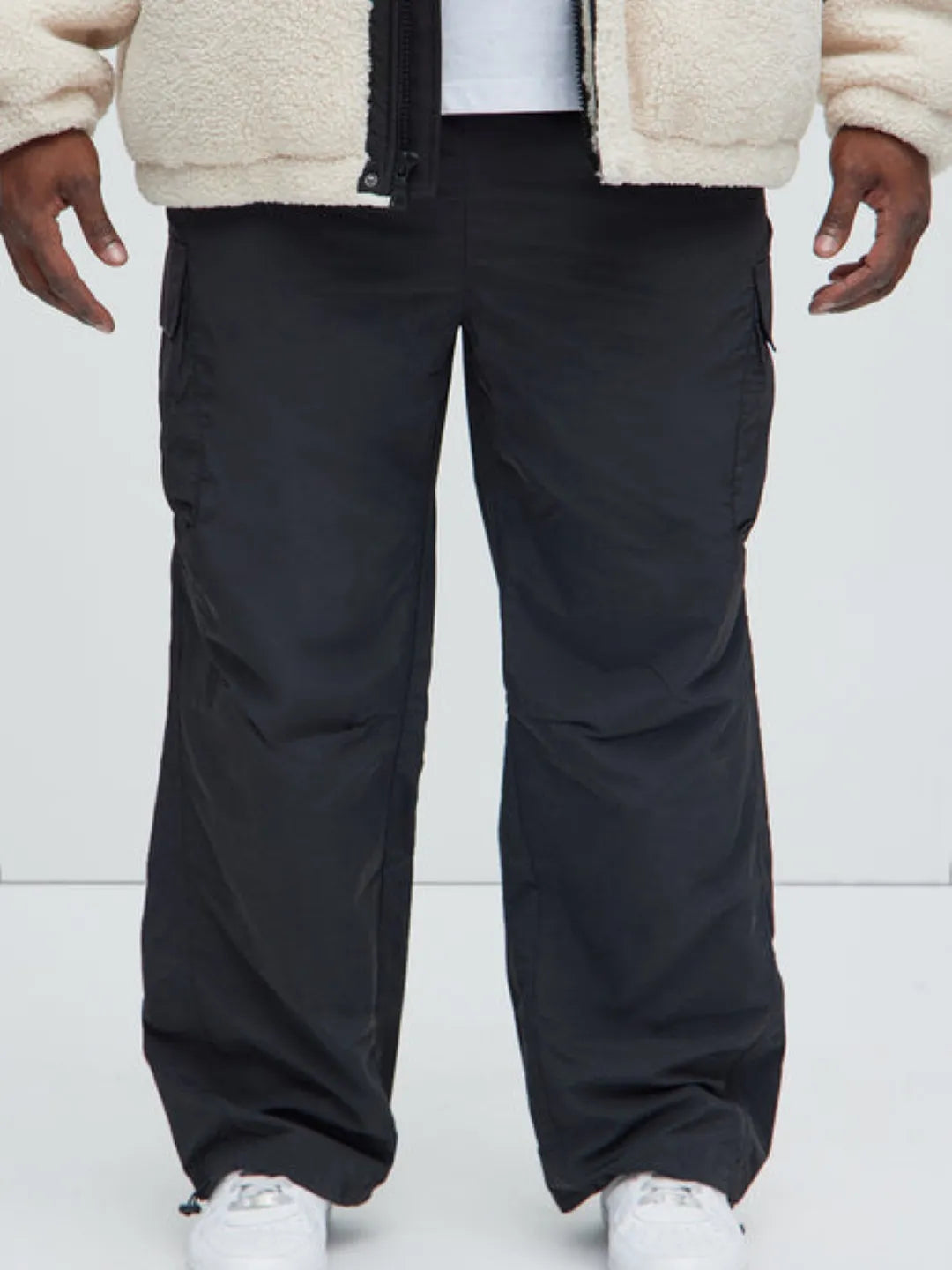 Person wearing black cargo pants with pockets on a white background