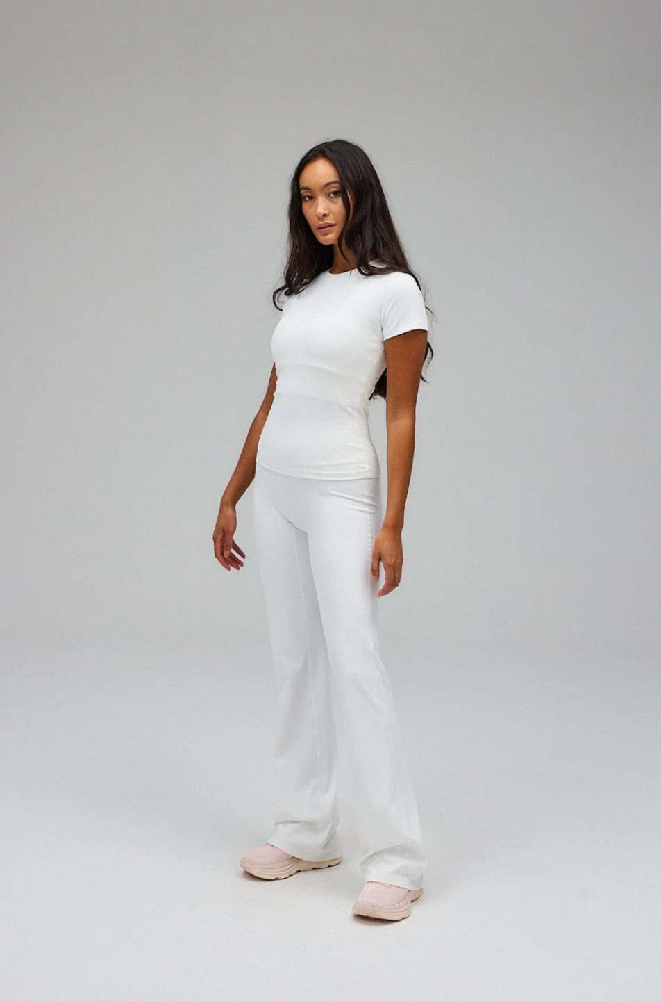 Woman wearing a white t-shirt and pants on a gray background