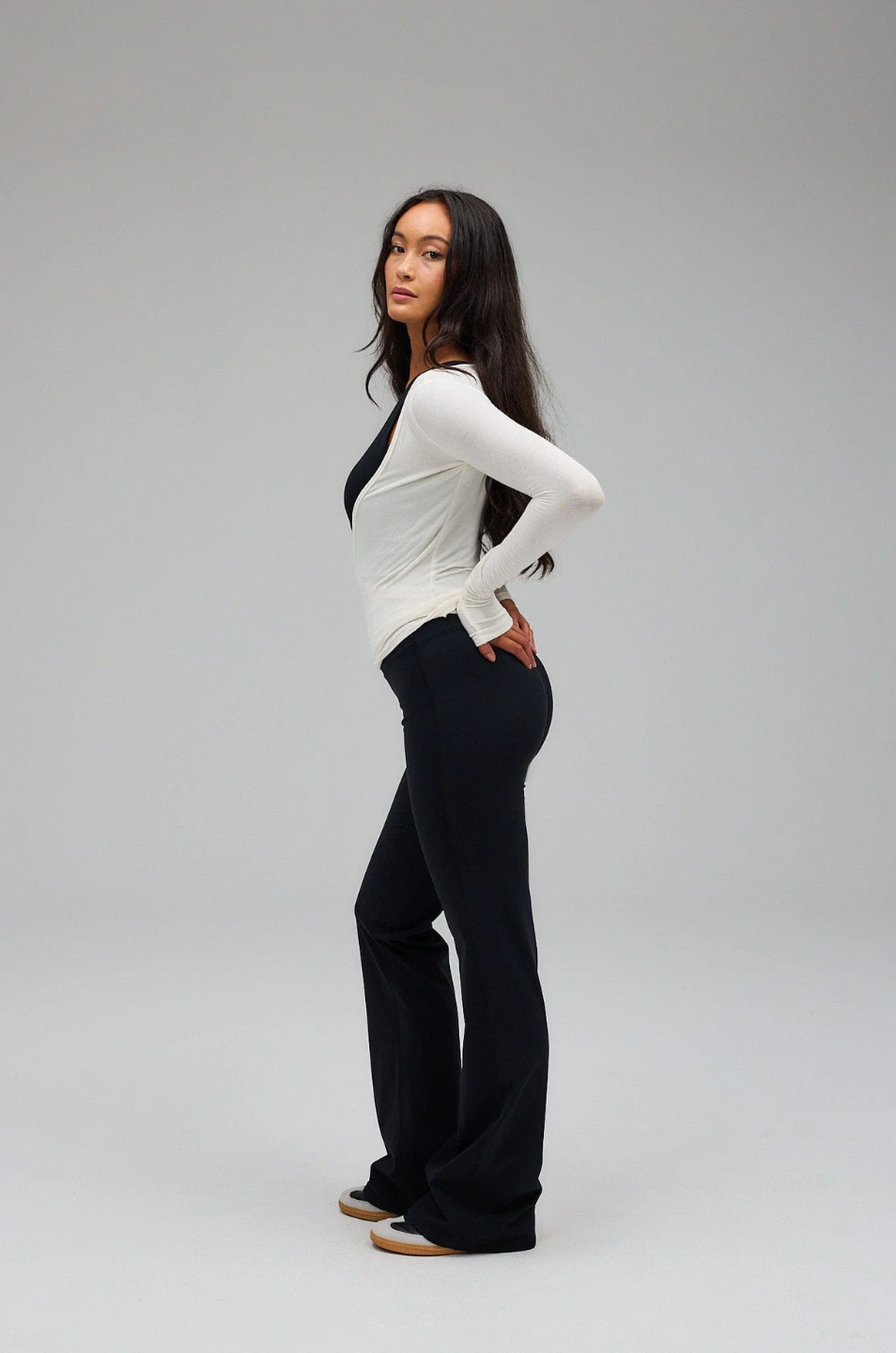 Woman wearing a white top and black pants on a gray background