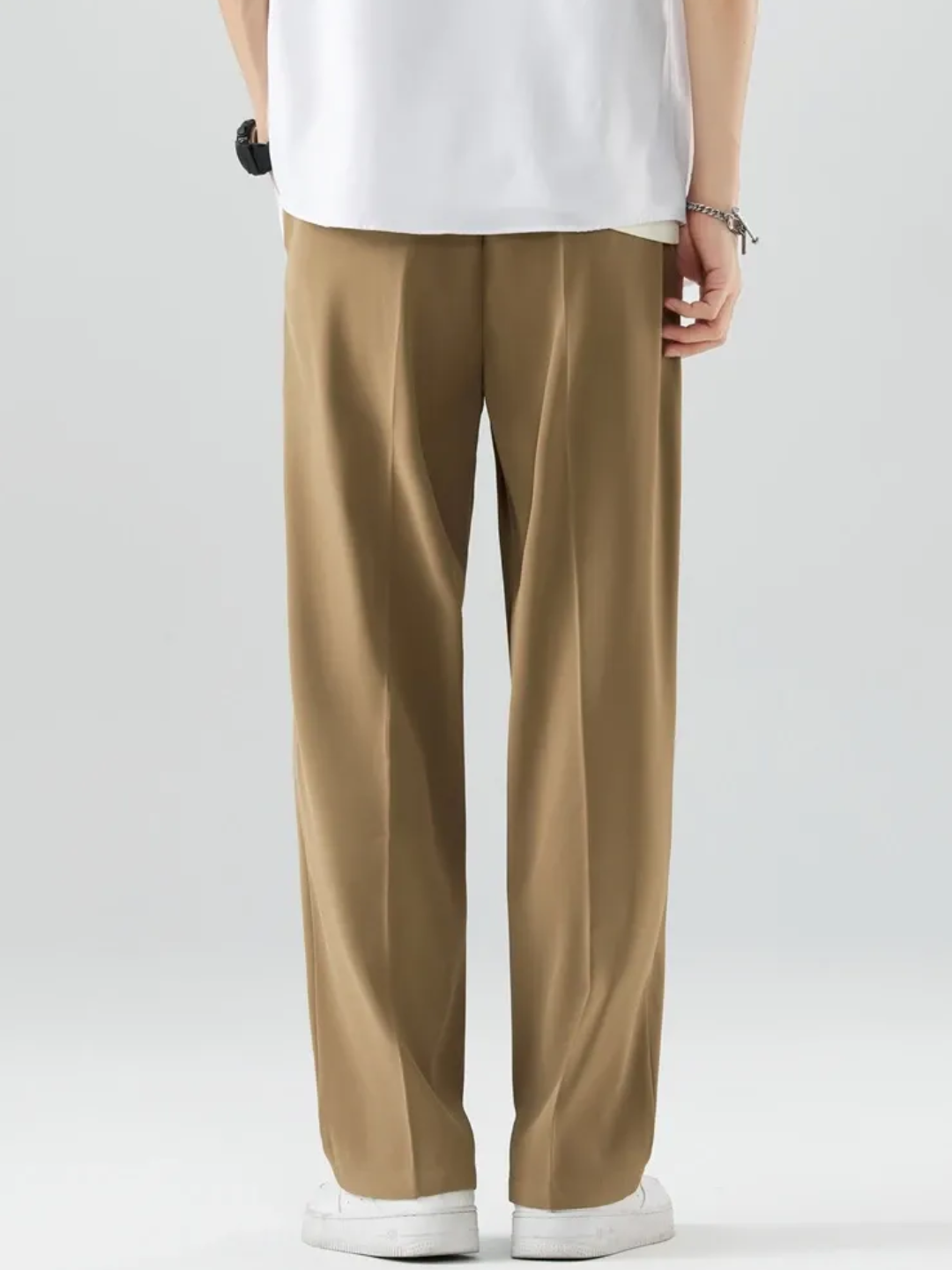 A person wearing brown Tek Air loose fit pants and a white shirt, standing against a white background.