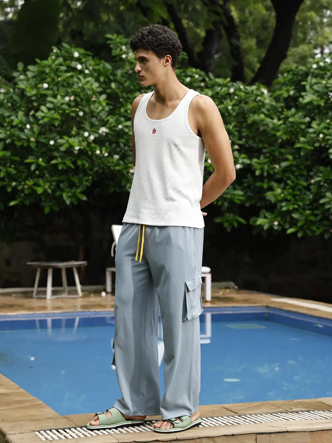 Man standing by a pool with greenery in the background