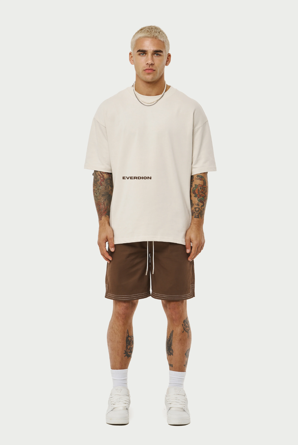 This image displays a pair of contrast stitch woven shorts, presented in a subtle beige color. The shorts feature a detailed design with a contrasting dark brown drawstring that adds a refined touch.