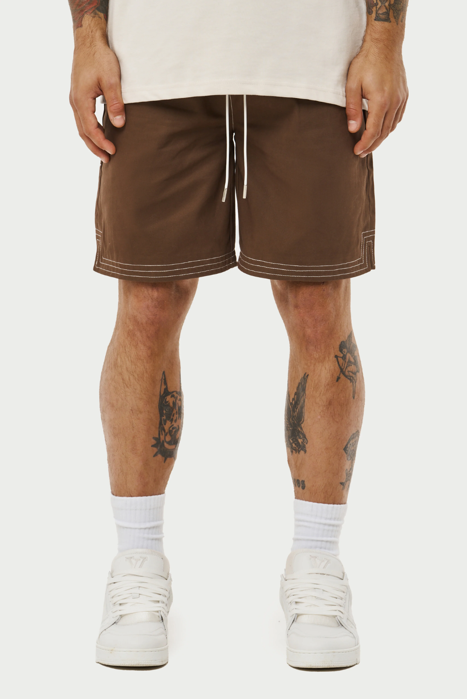 This image displays a model wearing a pair of contrast stitch woven shorts, perfect for a relaxed yet stylish look. The shorts are brown with a distinctive white contrast stitching that accentuates the seams and pockets, adding a modern touch to the classic design.