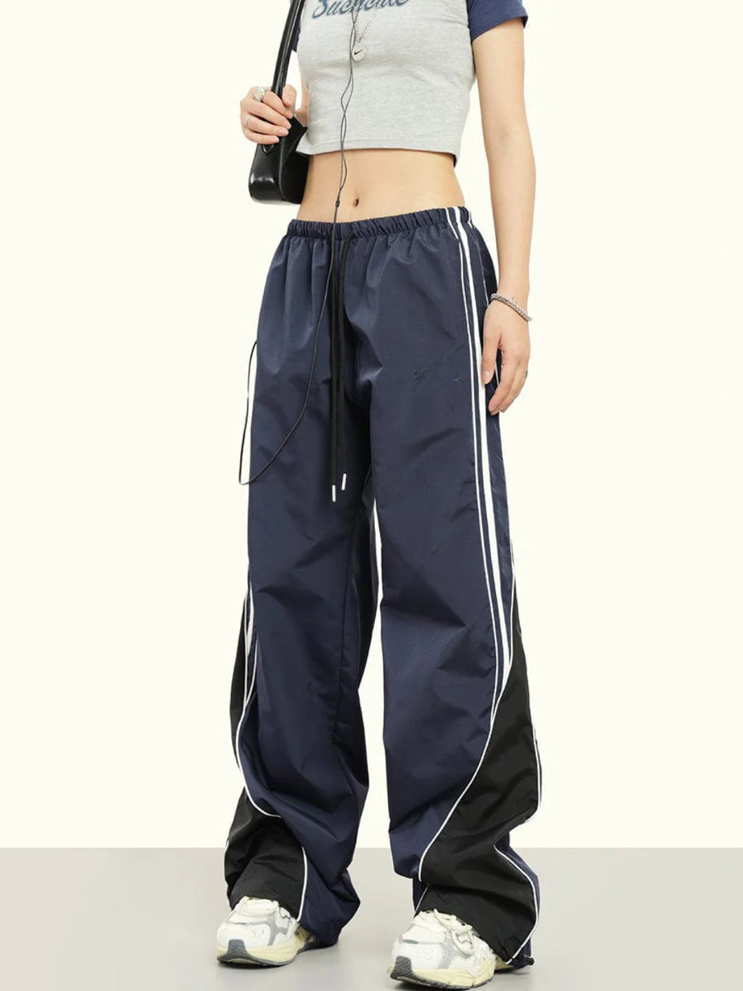 Blue striped parachute pants with white contrast piping, an elasticated waistband with adjustable drawstrings