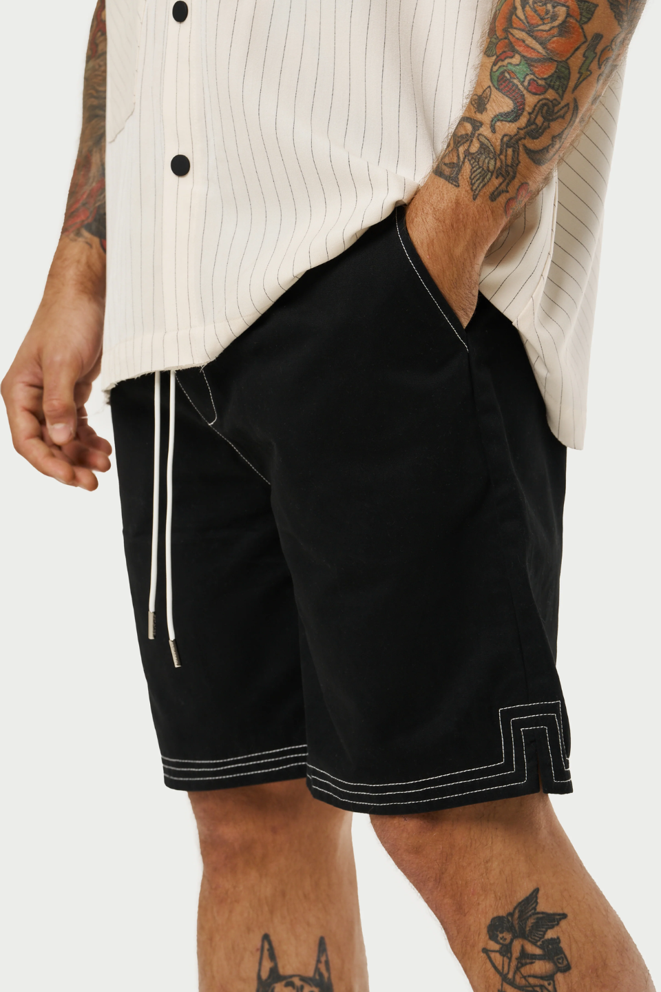 Model wearing a pair of contrast stitch woven shorts, perfect for a relaxed yet stylish look. The shorts are Black with a distinctive white contrast stitching that accentuates the seams and pockets, adding a modern touch to the classic design.