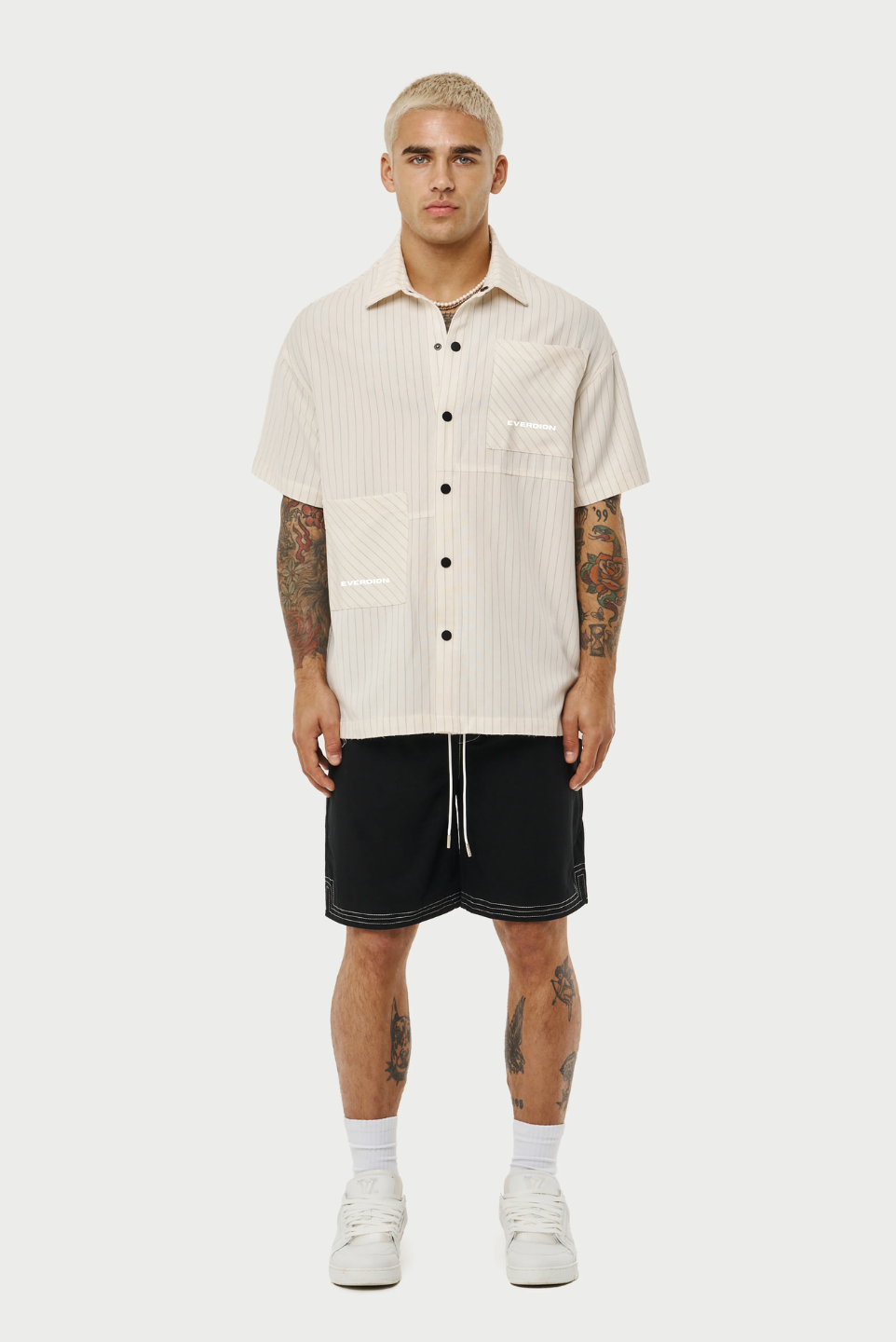 Model wearing a pair of contrast stitch woven shorts, perfect for a relaxed yet stylish look. The shorts are Black with a distinctive white contrast stitching that accentuates the seams and pockets, adding a modern touch to the classic design.
