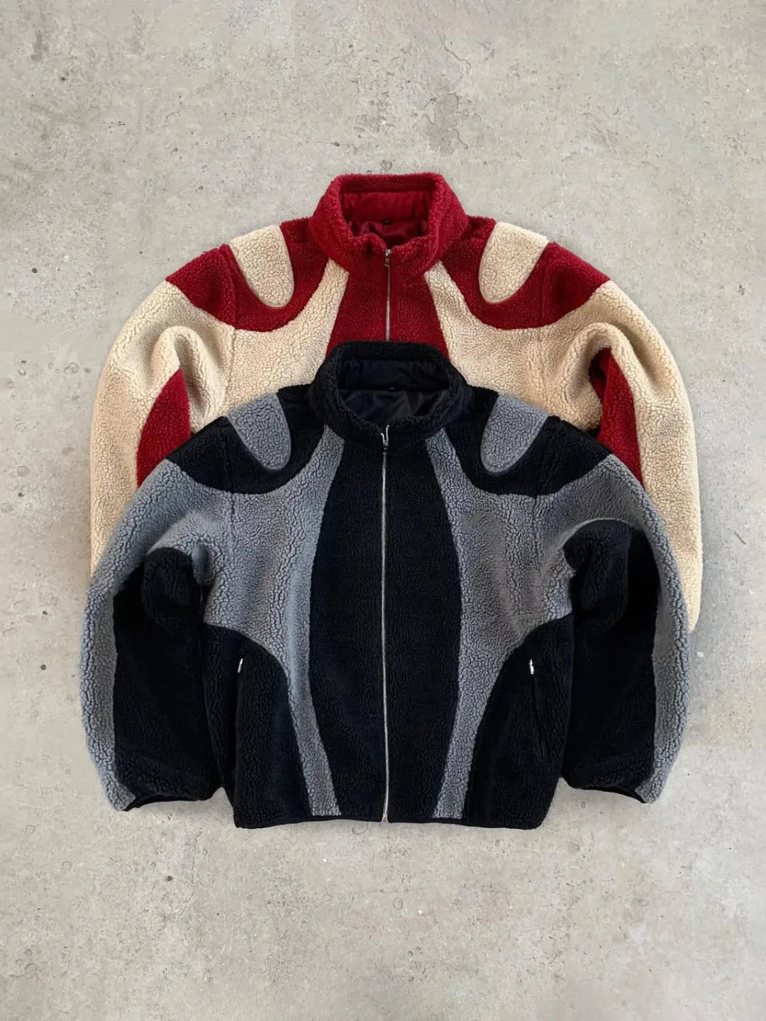 Three different colored jackets stacked on a concrete surface