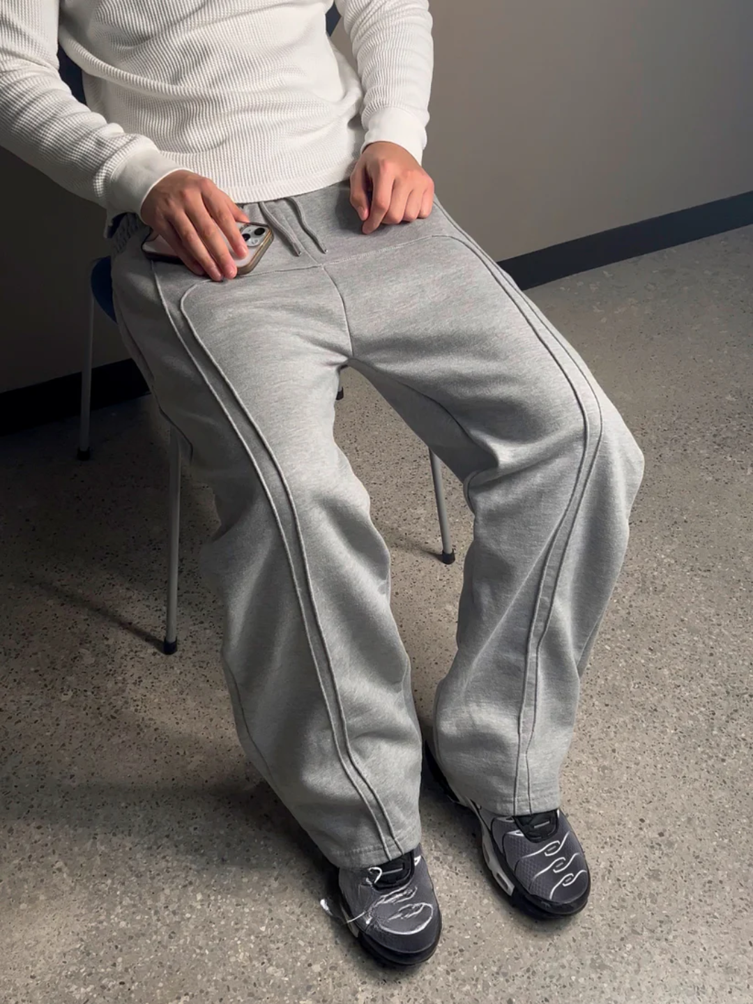 Person wearing gray sweatpants sitting on a chair indoors.