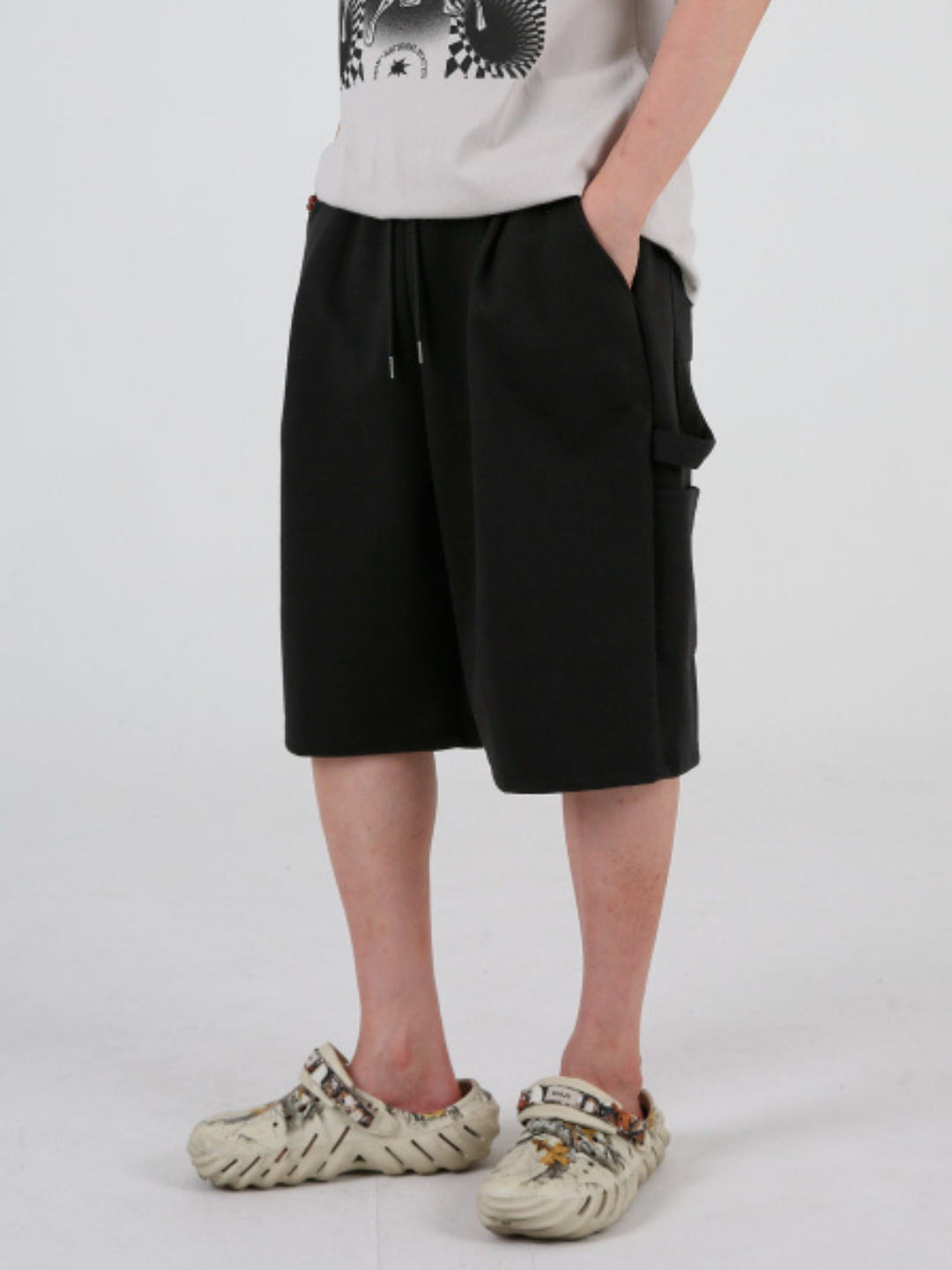 A pair of gray sweatpants-style shorts with an elastic waistband and drawstring, featuring exposed pocket seams. The shorts are designed with two back pockets.