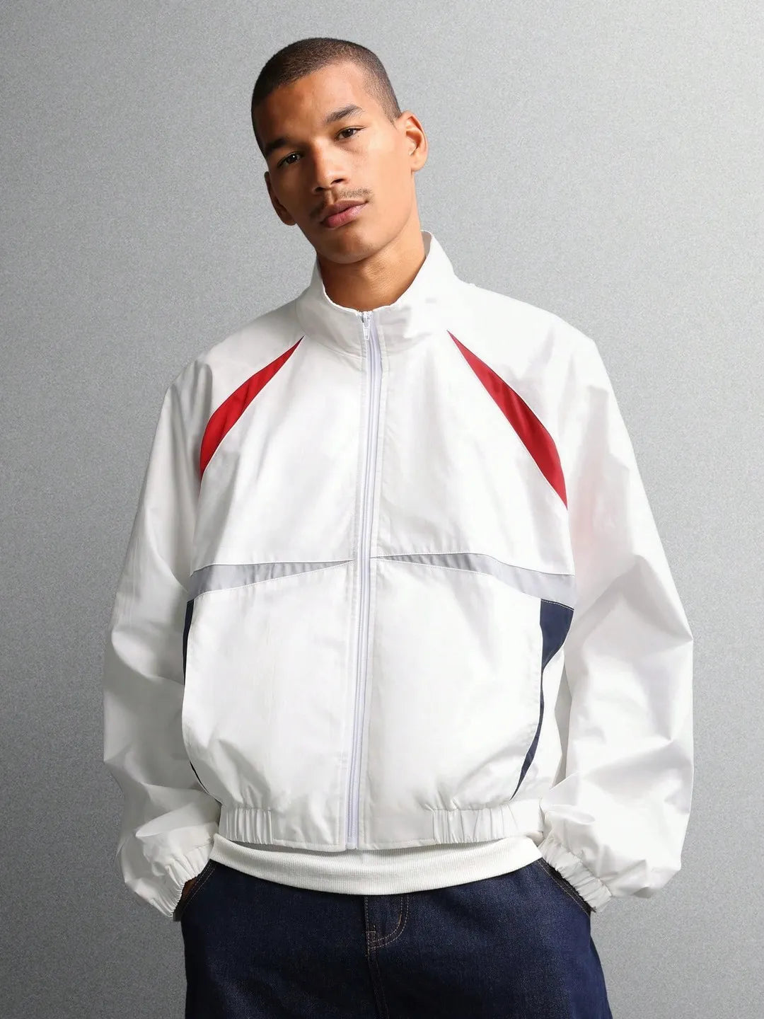 Person wearing a white jacket with red accents on a gray background