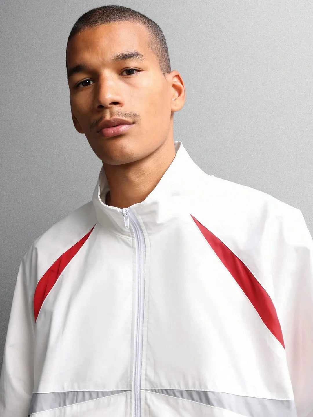 Man wearing a white jacket with red accents against a gray background