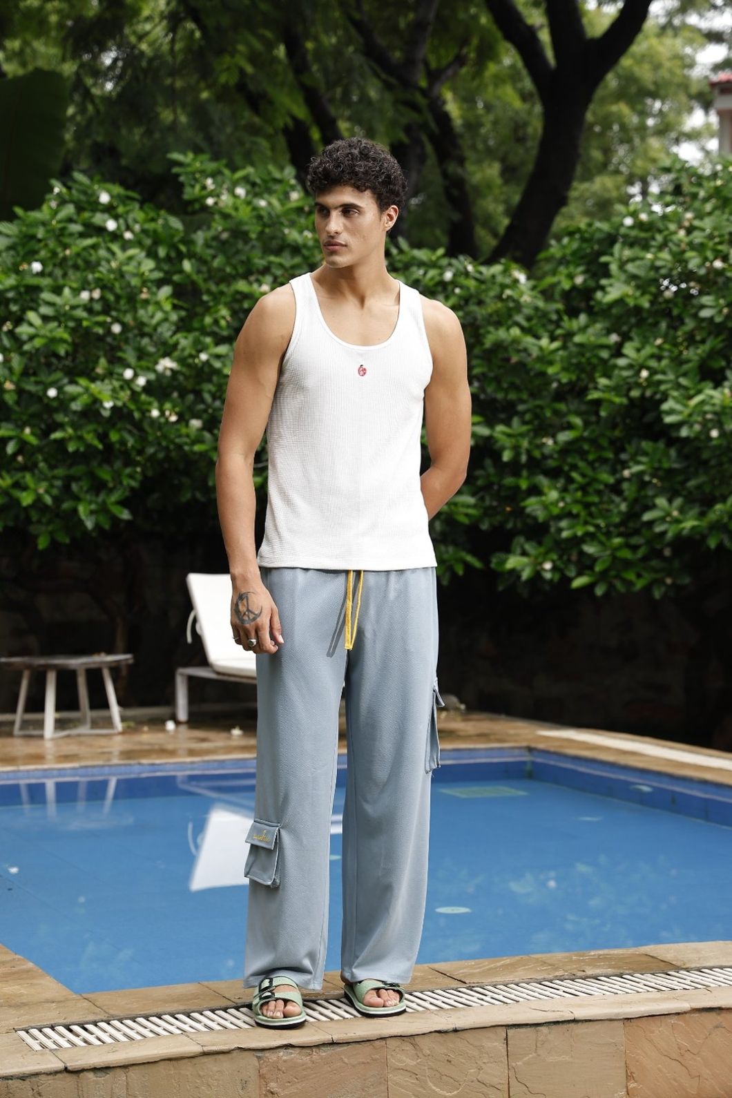 Man standing by a pool with greenery in the background