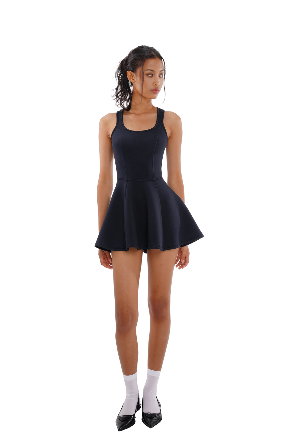 A woman wearing a navy blue sleeveless tennis dress with a square neckline and pleated skirt.