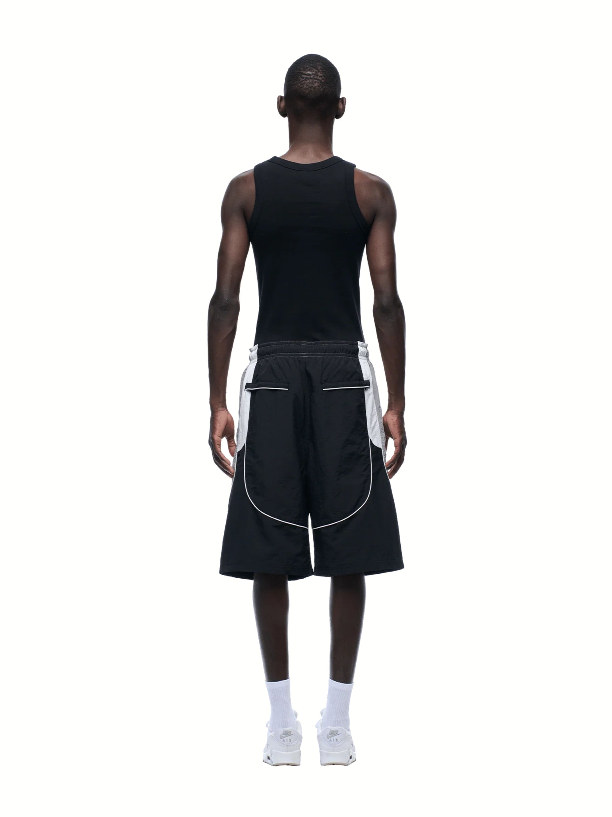 Person wearing a black sleeveless top and shorts on a white background