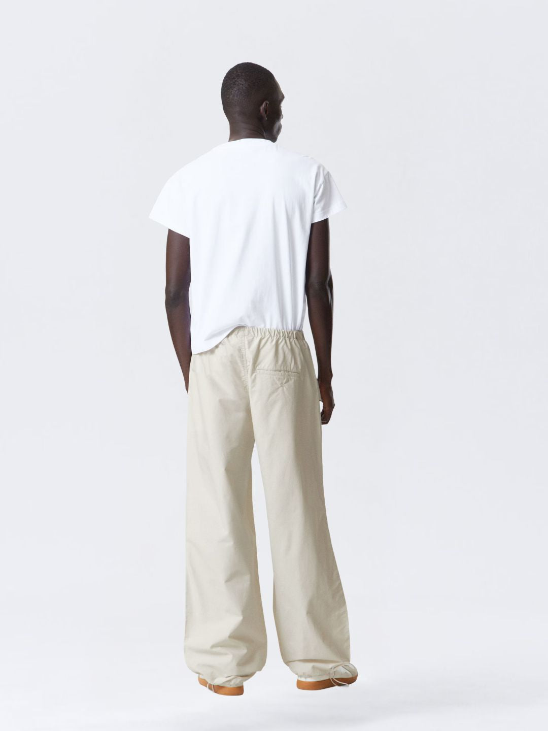 Person wearing a white t-shirt and beige pants on a white background