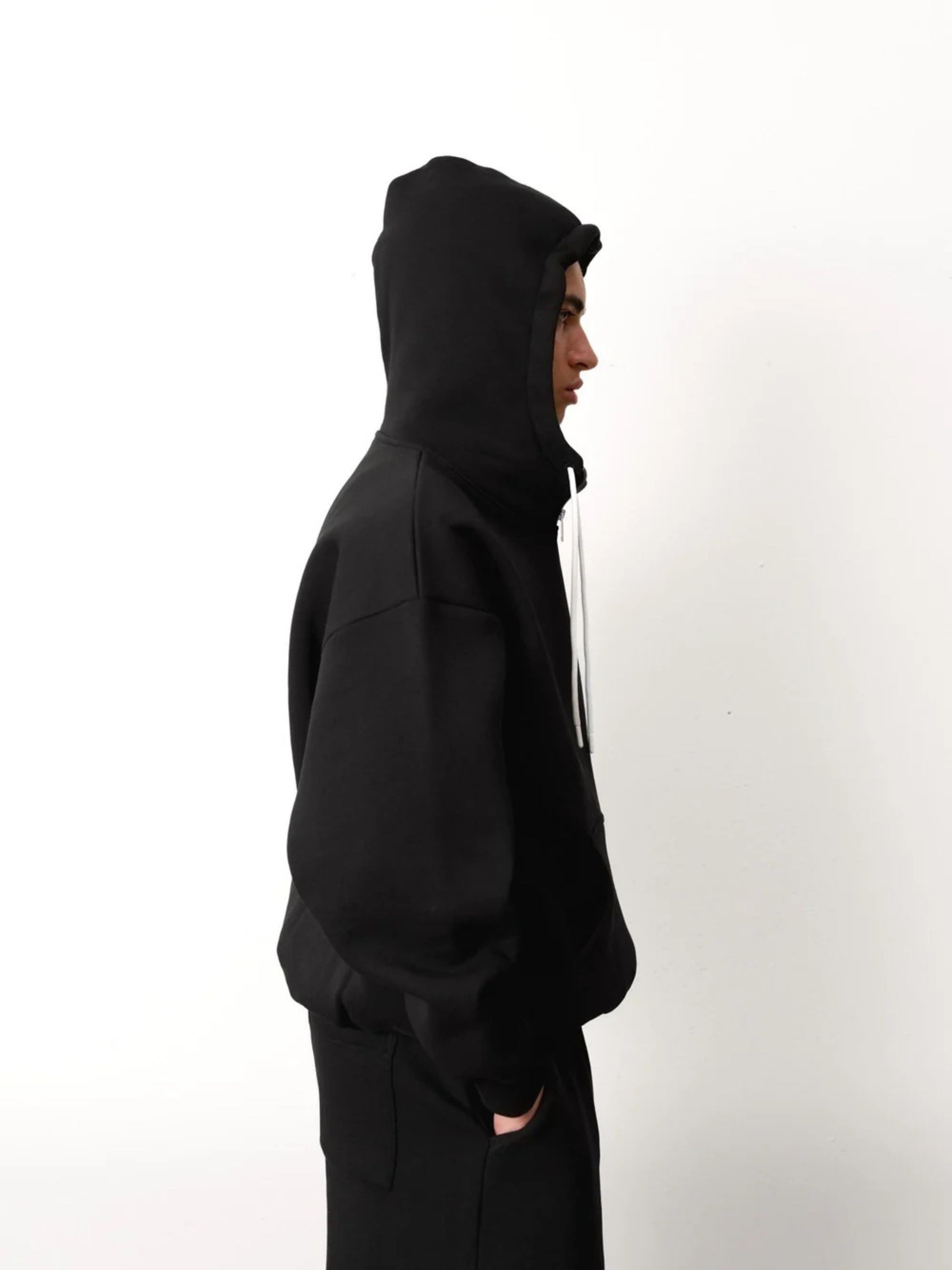 Person wearing a black hoodie against a white background