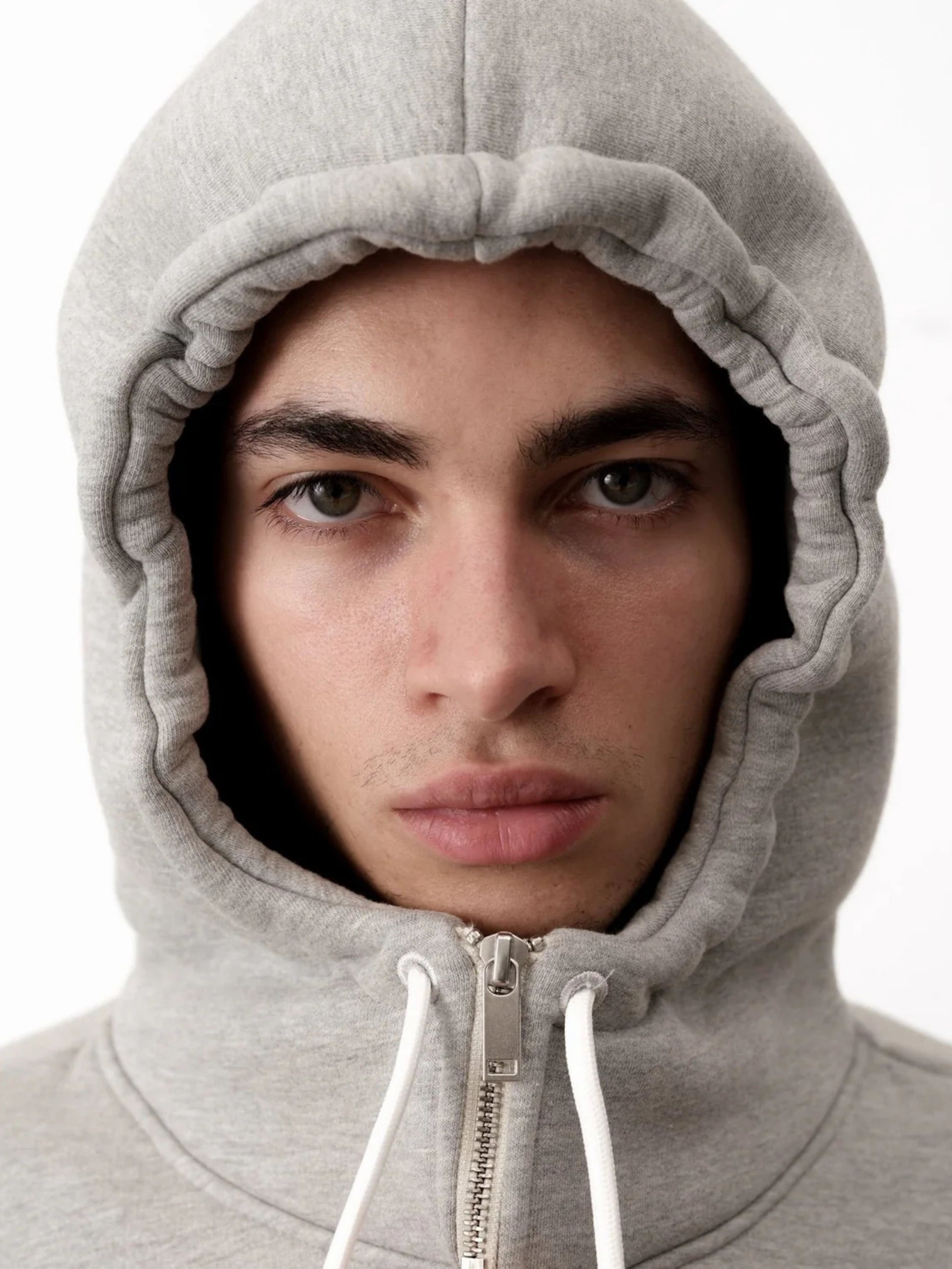 Person wearing a gray hoodie with a neutral background