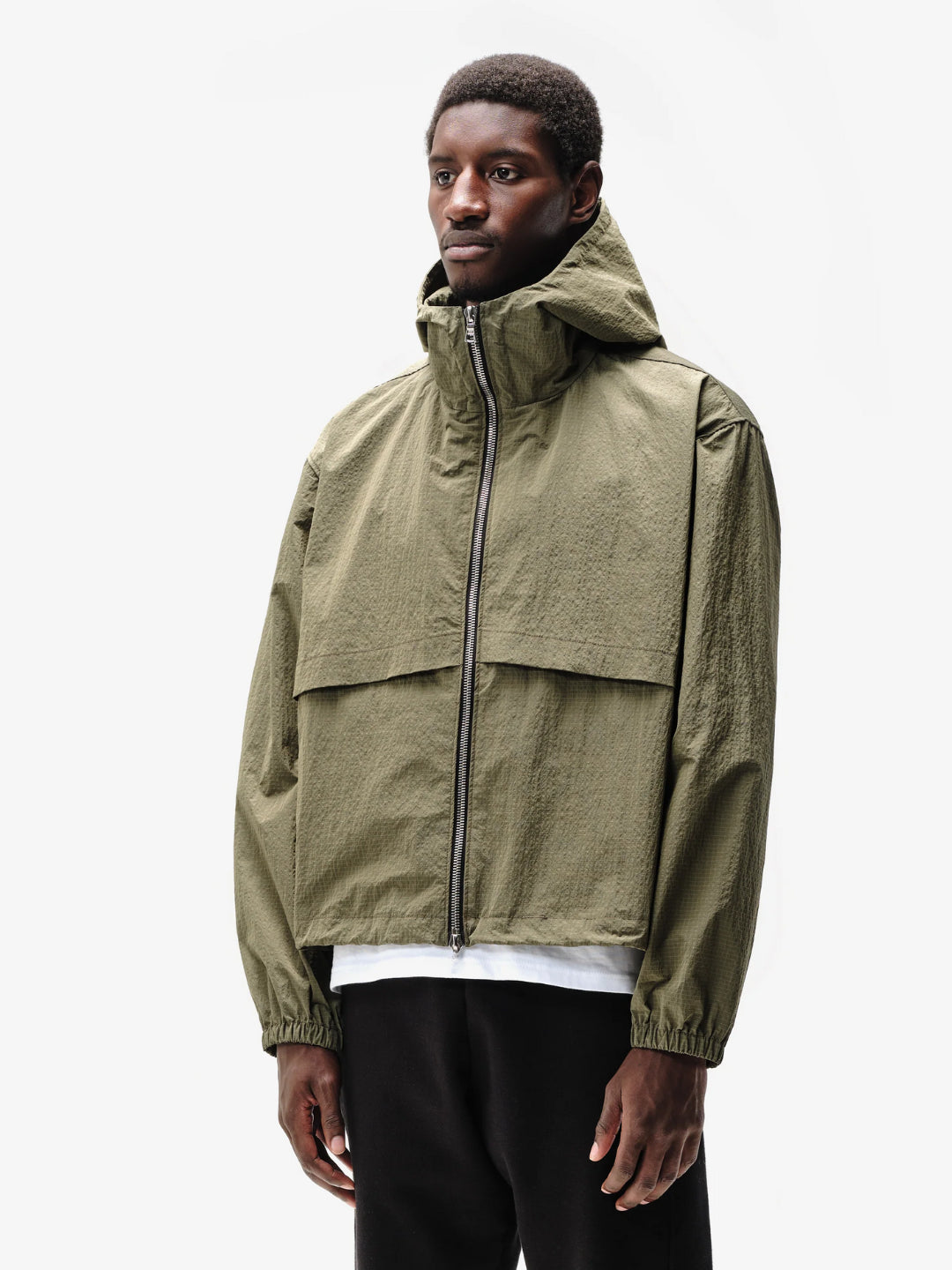 A person wearing a hooded green jacket with a front zipper and an adjustable hood.