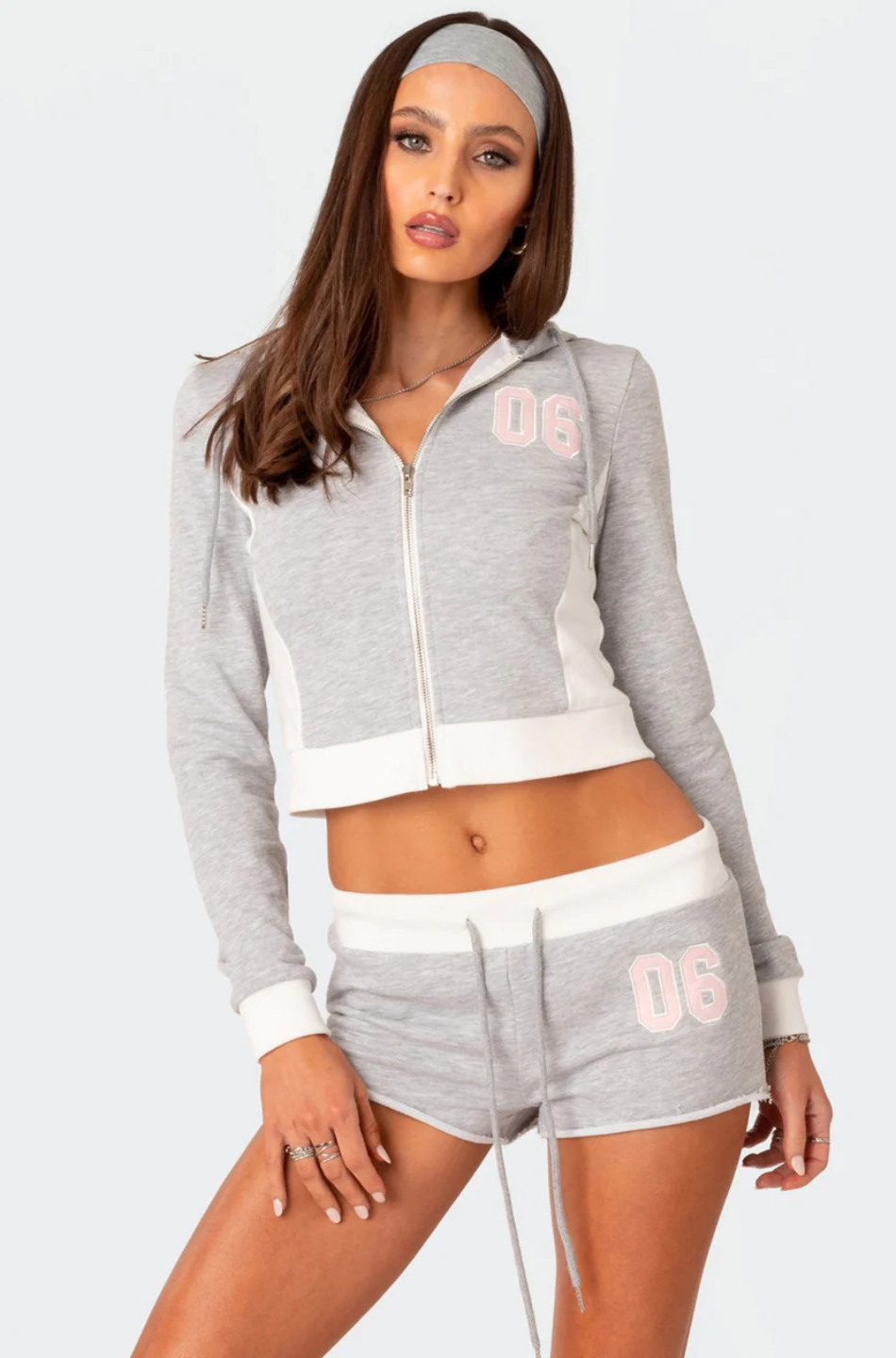 A female model wearing a grey Paparazzi hoodie and matching shorts with a text pattern.