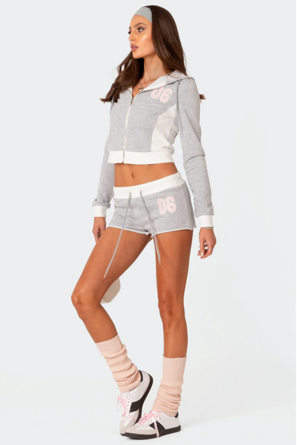 A female model wearing a grey Paparazzi hoodie and matching shorts with a text pattern.