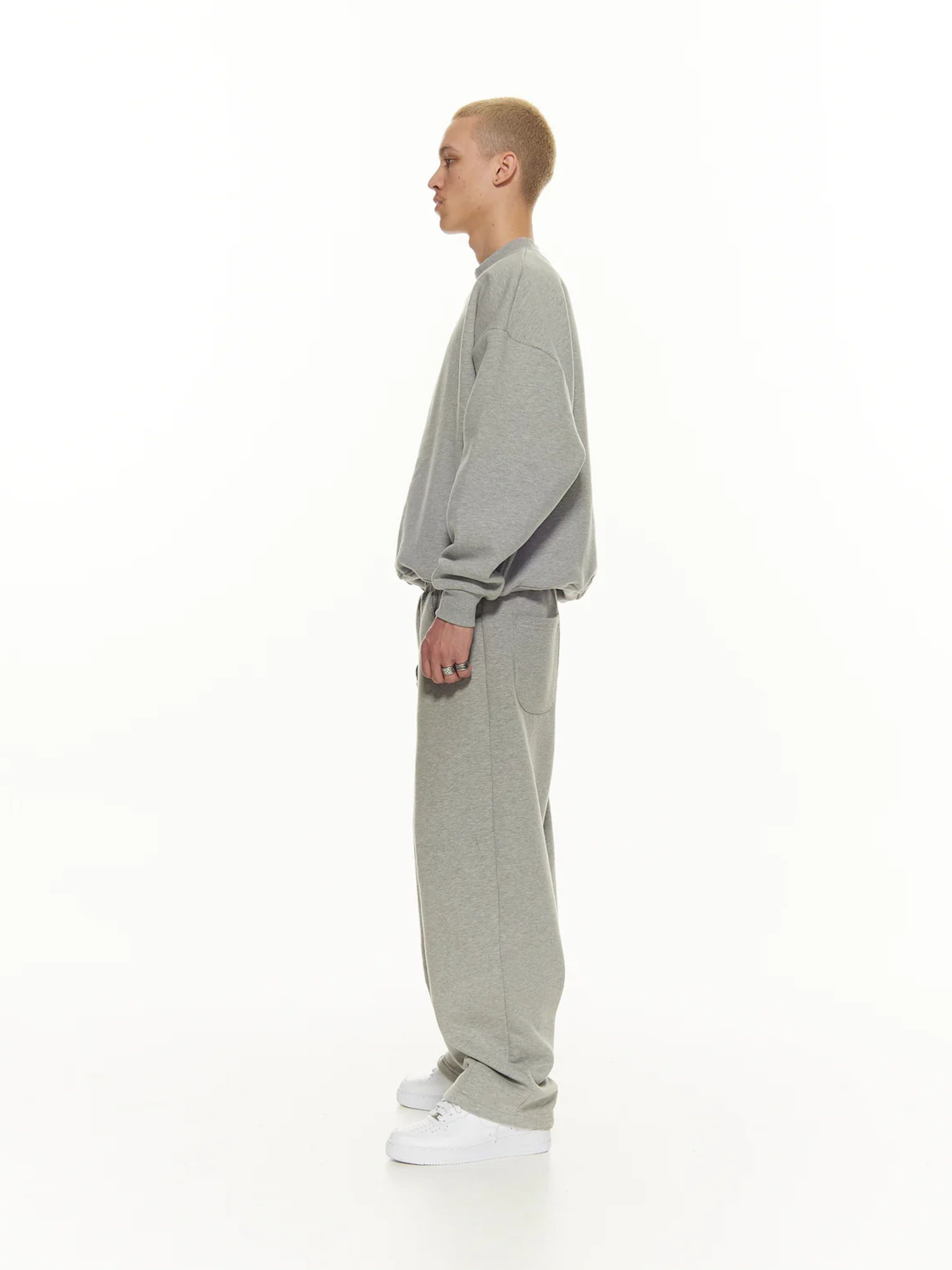 Person wearing a gray tracksuit on a white background