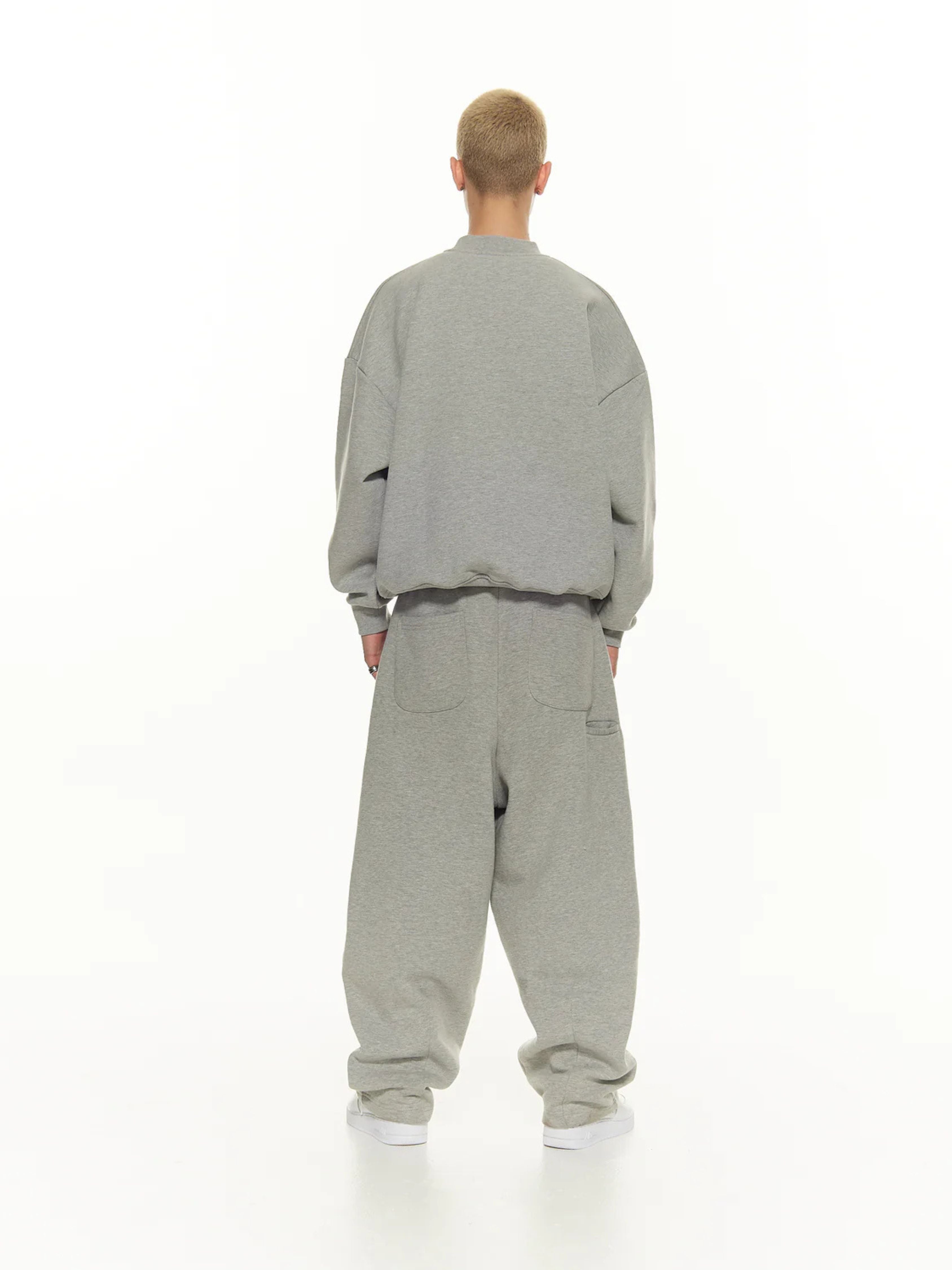 Person wearing a gray tracksuit on a white background