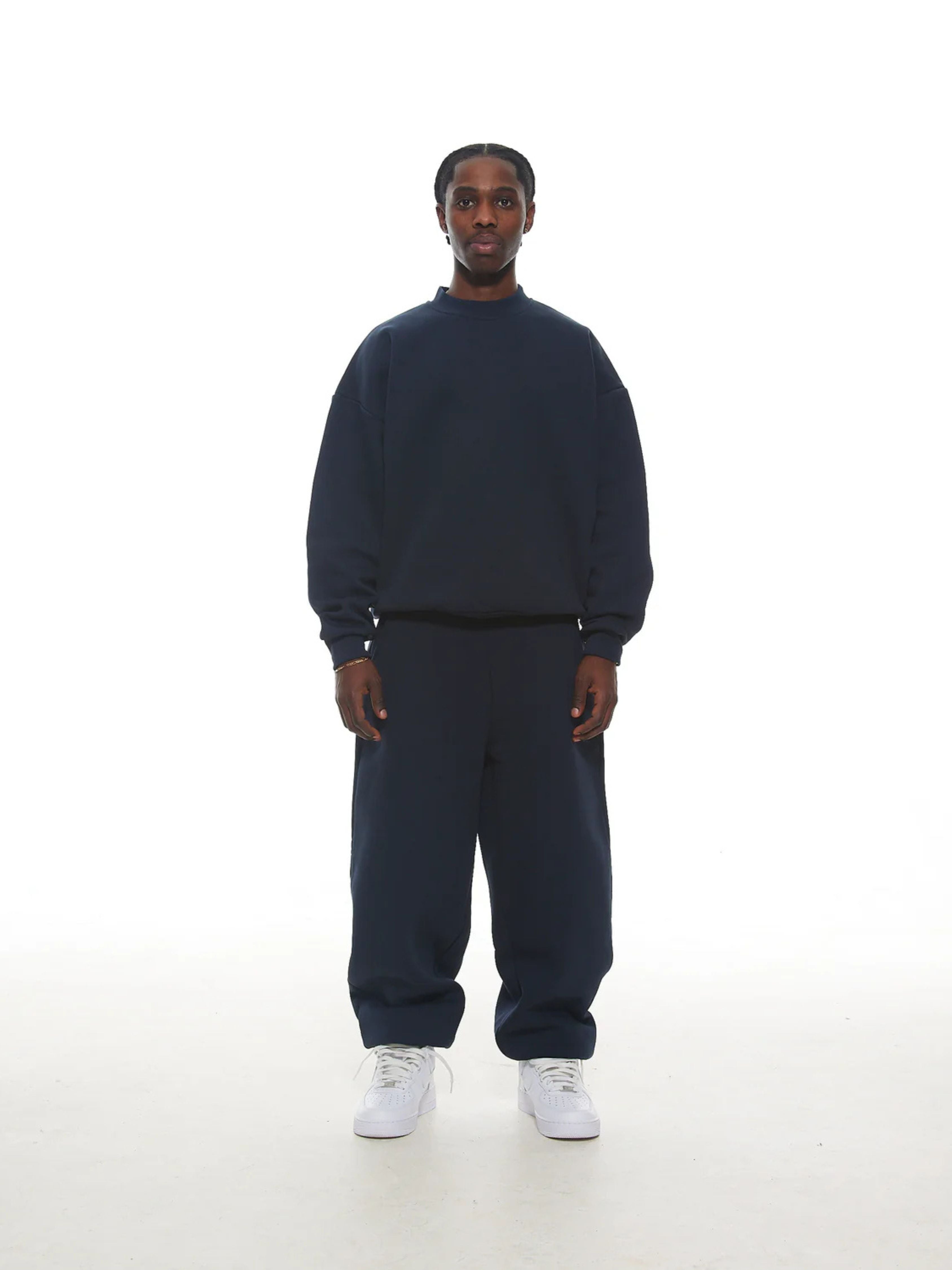 Person wearing a navy blue sweatshirt and pants on a white background