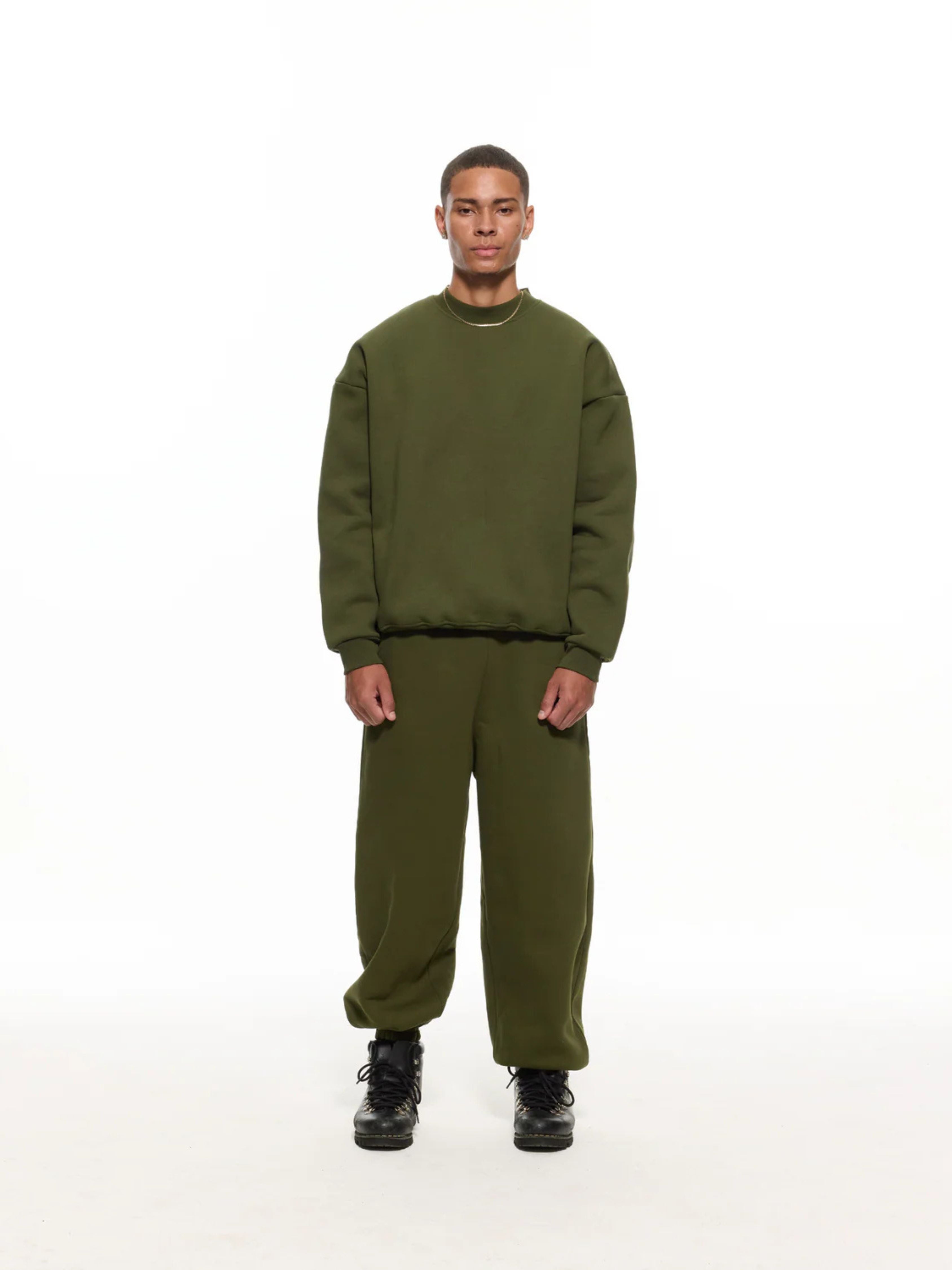 Person wearing an olive green sweatshirt and pants on a white background