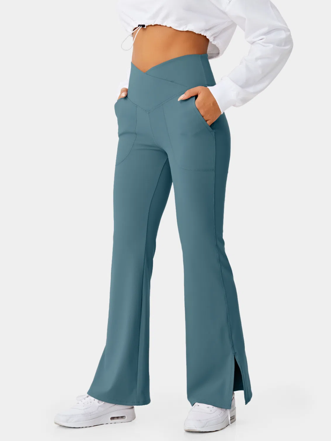 A person wearing teal flare leggings with a split hem, paired with a white cropped top and white sneakers.