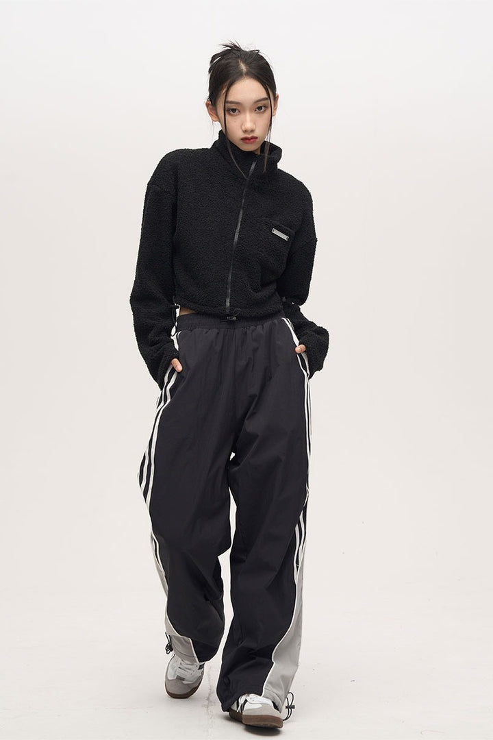 black striped parachute pants with white contrast piping, an elasticated waistband with adjustable drawstrings