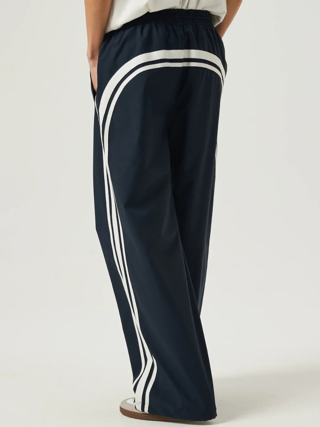 Navy tracksuit with white stripes on a plain background