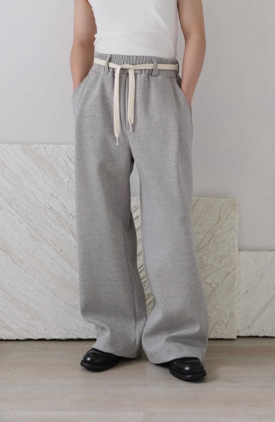 wide leg gray pants with a cotton belt, a white top, and black shoes.