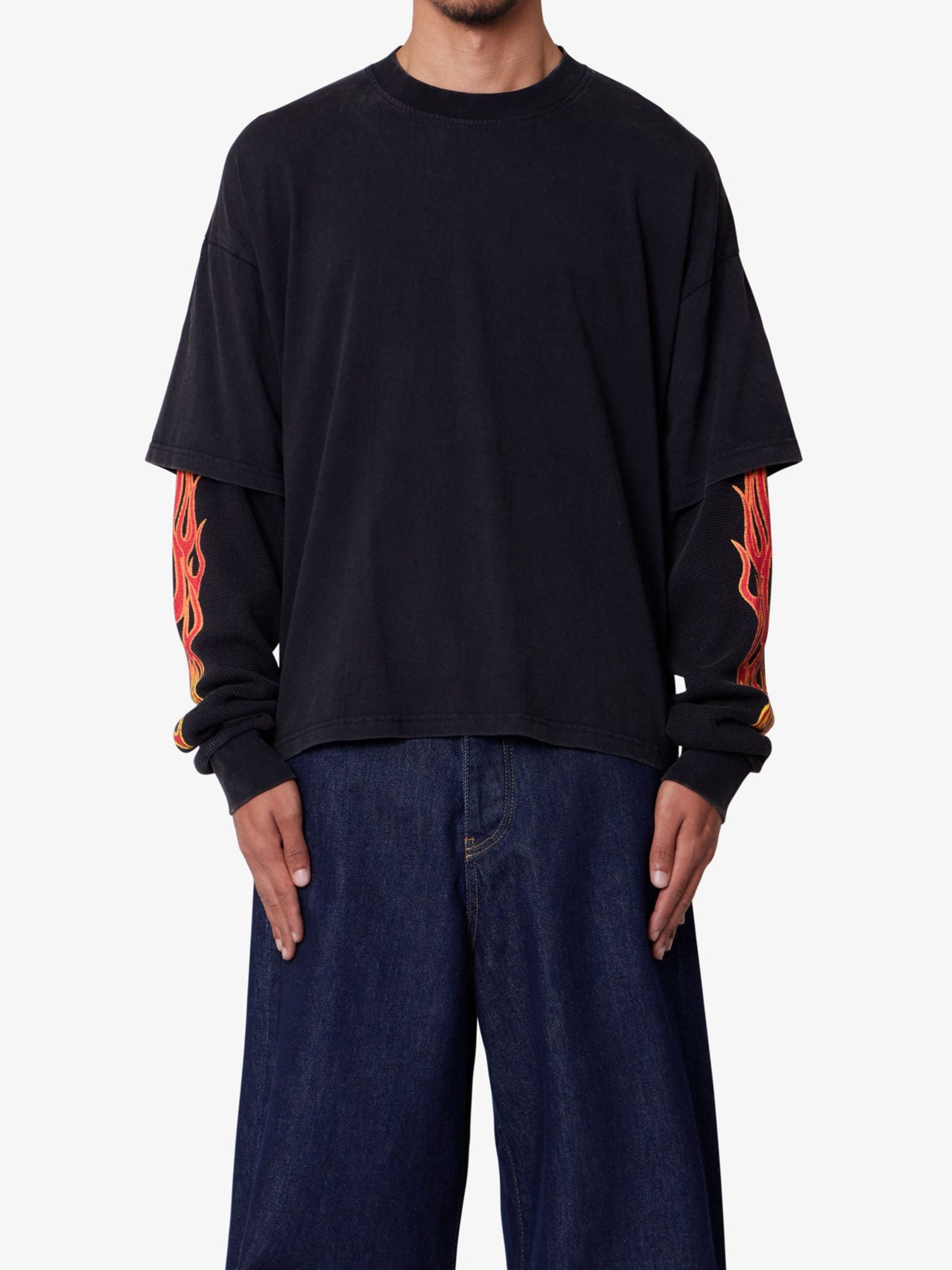 Person wearing a black long-sleeve shirt with red designs on the sleeves against a white background