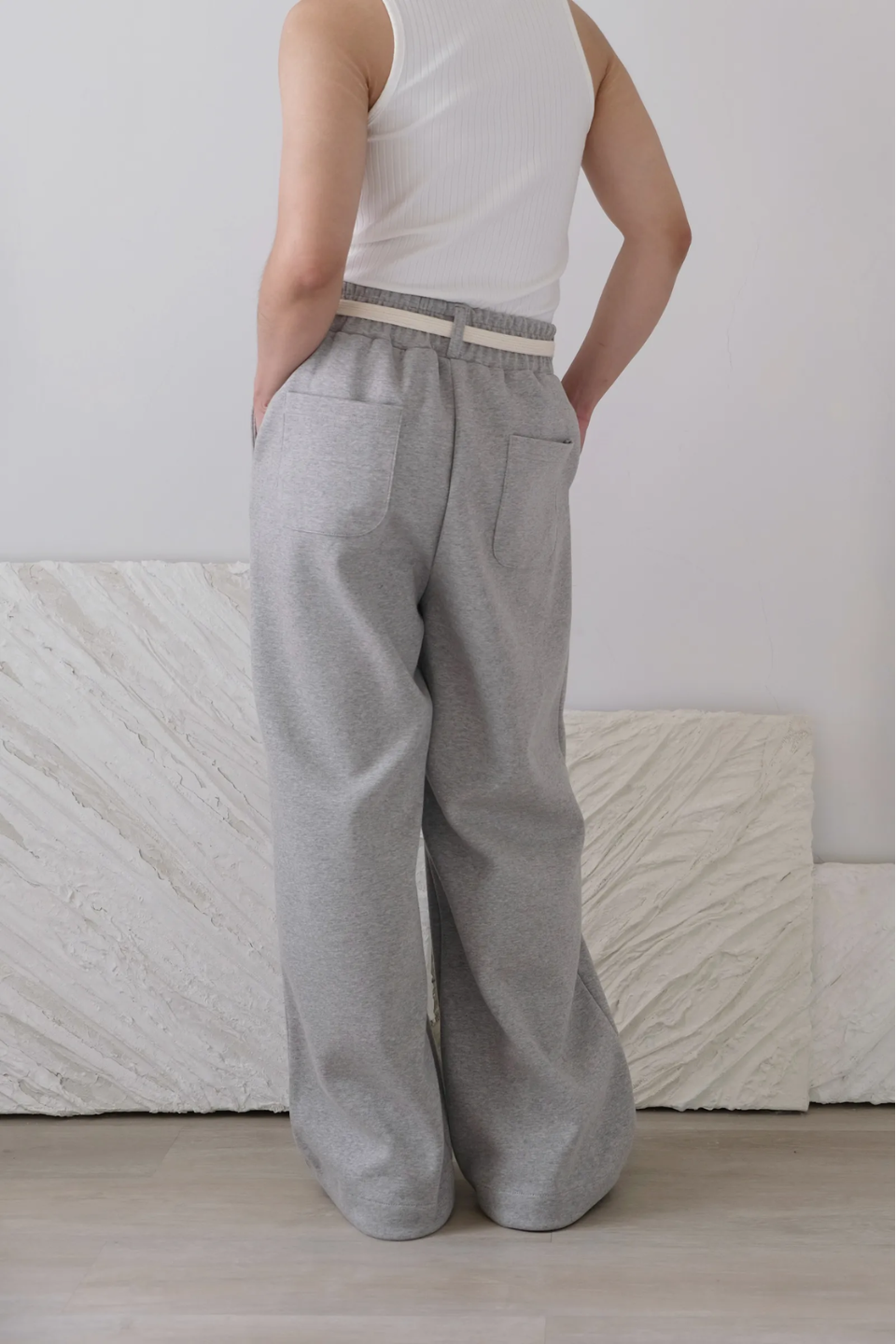 wide leg gray pants with a cotton belt, a white top, and black shoes.