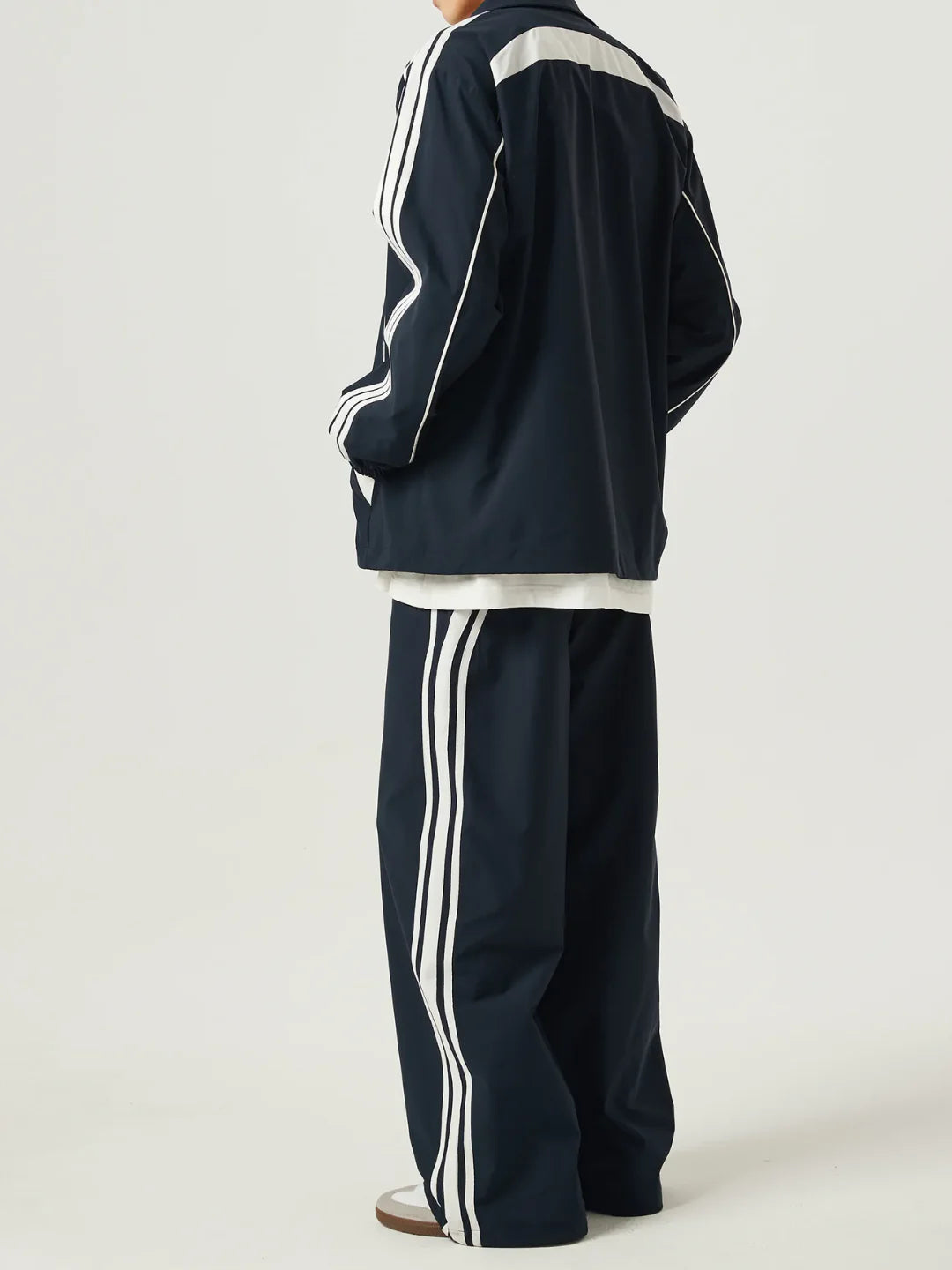 Navy tracksuit with white stripes on a plain background