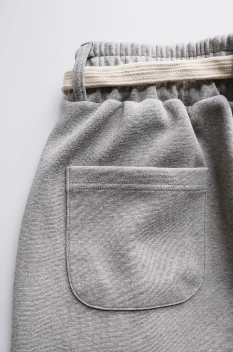 wide leg gray pants with a cotton belt, a white top, and black shoes.