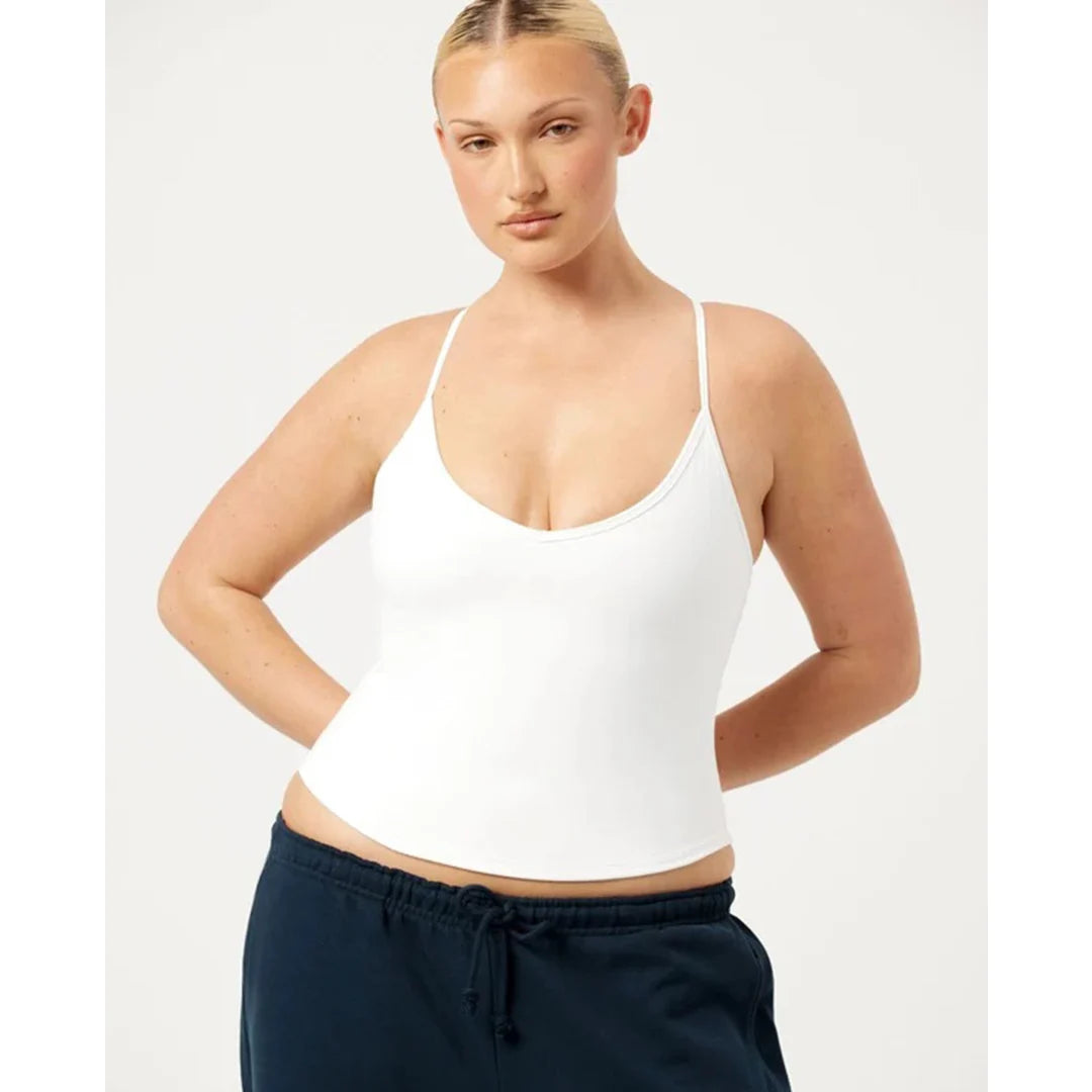 Woman wearing a white tank top and navy pants on a white background