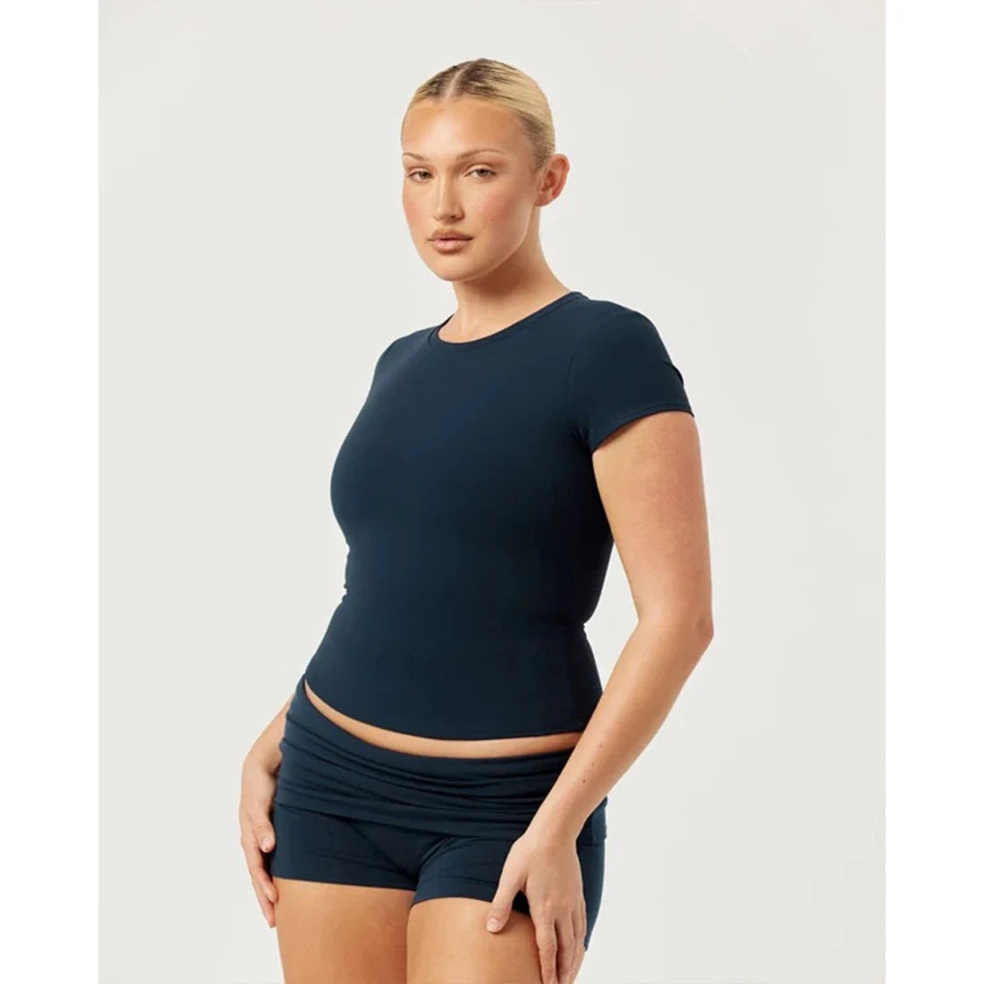 Woman wearing a navy blue athletic outfit on a light gray background