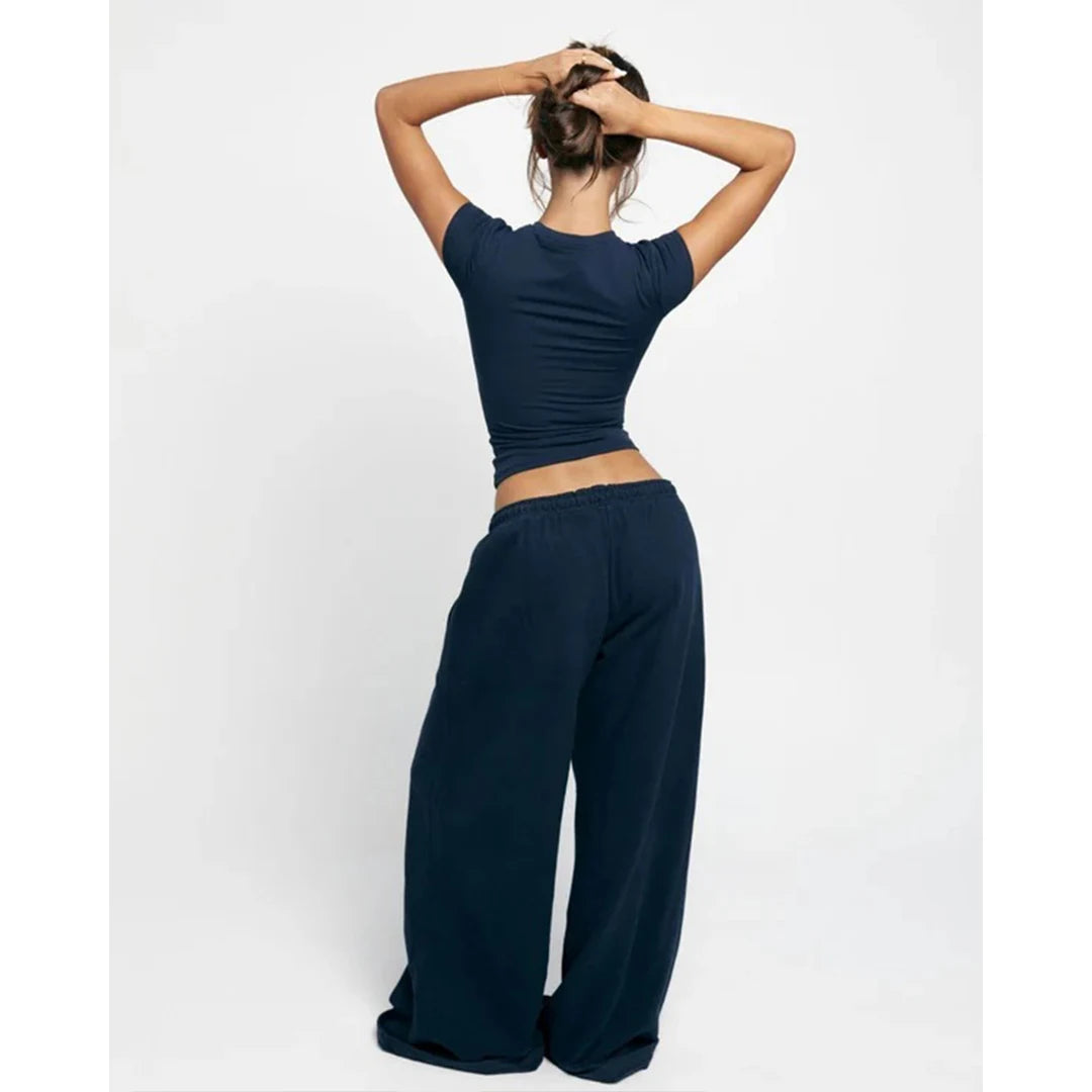 Person wearing a navy blue crop top and wide-leg pants on a white background