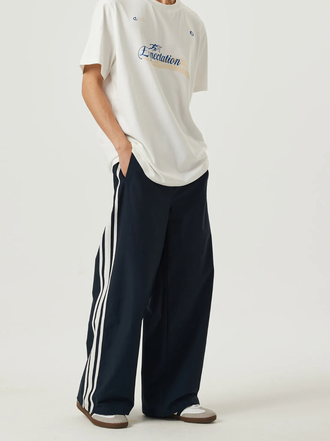 navy blue race track pants with white stripes on the side and an elasticated waistband with a drawstring