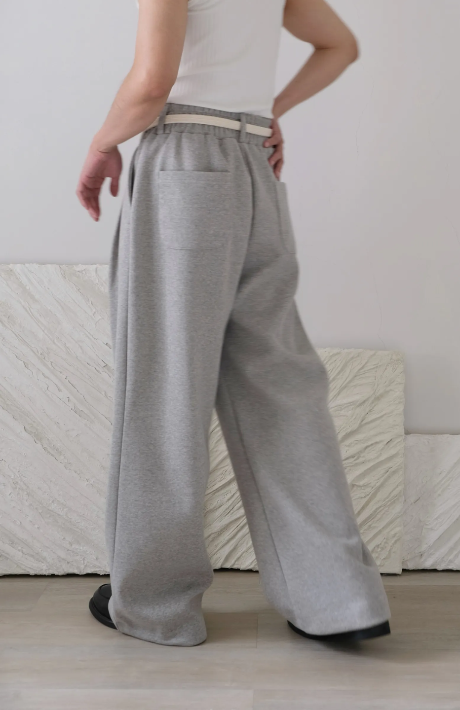 wide leg gray pants with a cotton belt, a white top, and black shoes.