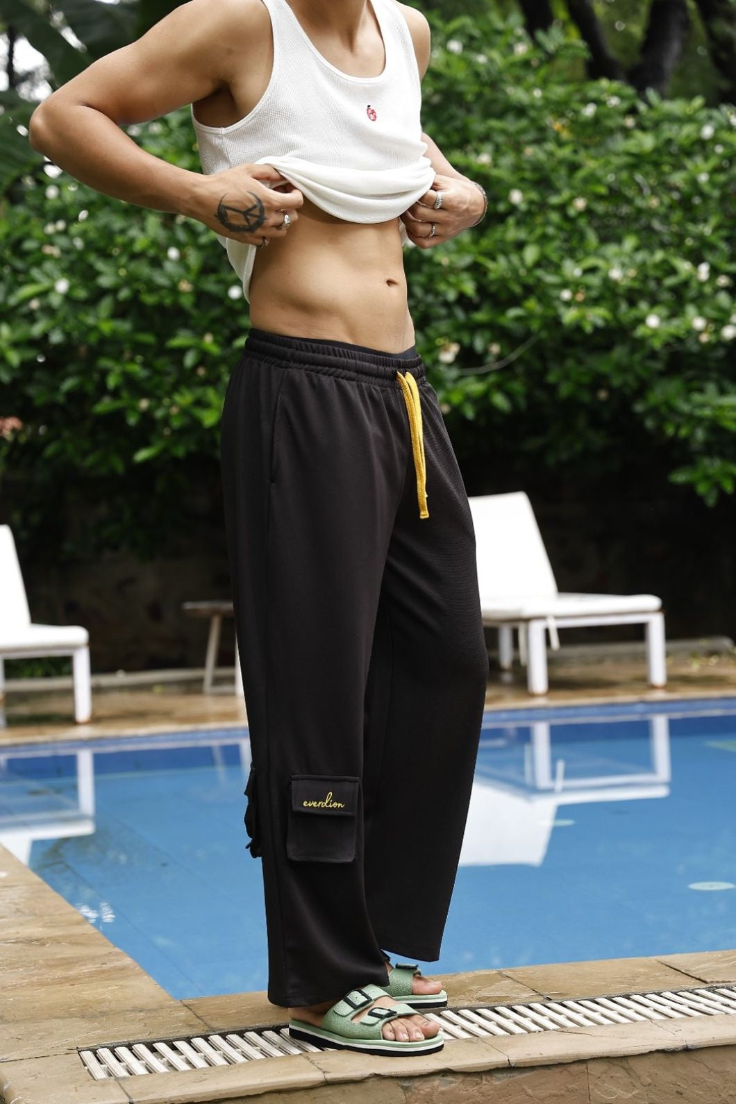 Two people standing by a pool with greenery in the background