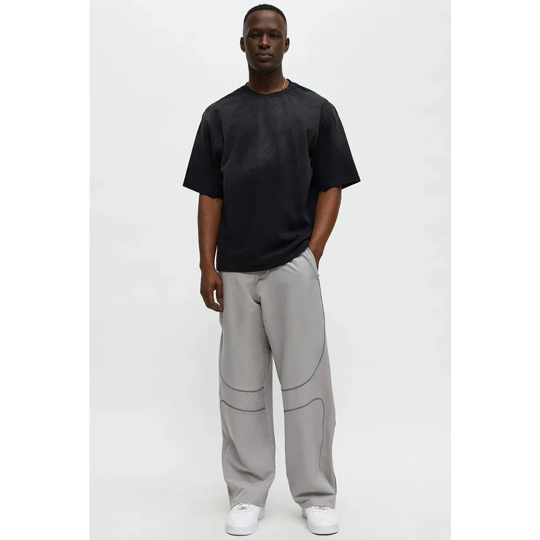 Person wearing a black t-shirt and gray pants on a white background