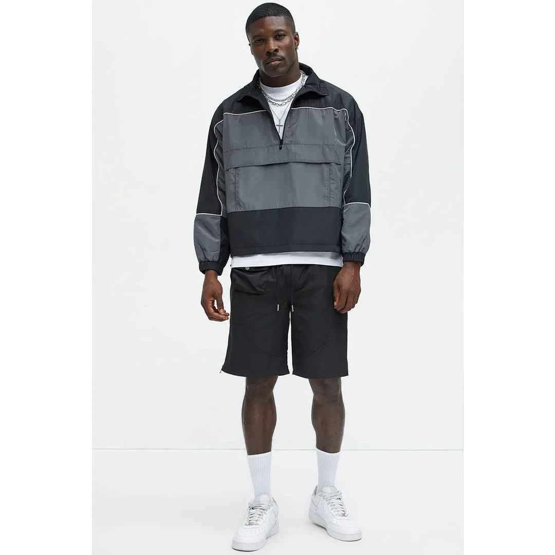 Man wearing a black and gray jacket with shorts on a white background