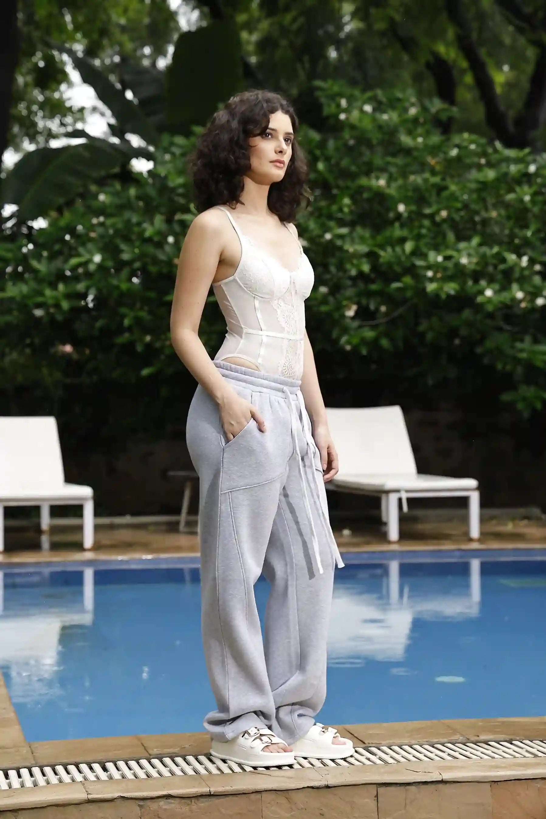 Woman standing by a pool with greenery in the background