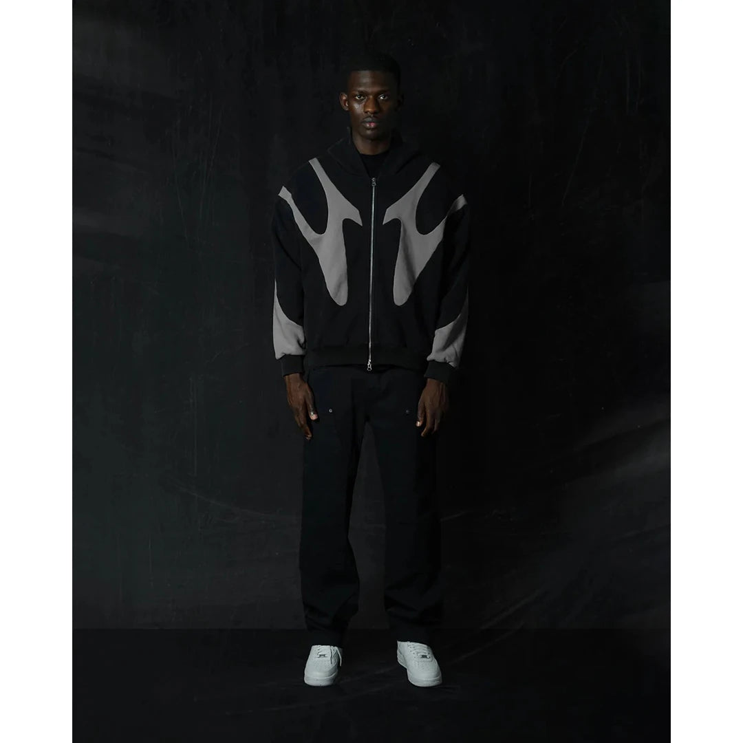 Person wearing a black and gray hoodie with flame design on a dark background